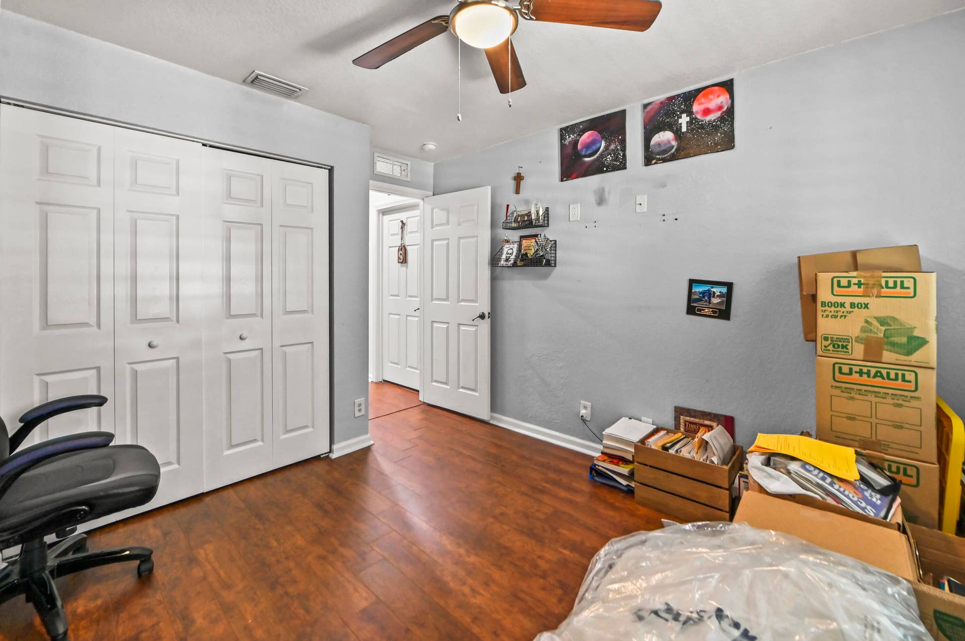 Wood-finish flooring, bi-fold closet doors, ceiling fan with integrated lighting, and a paneled interior door