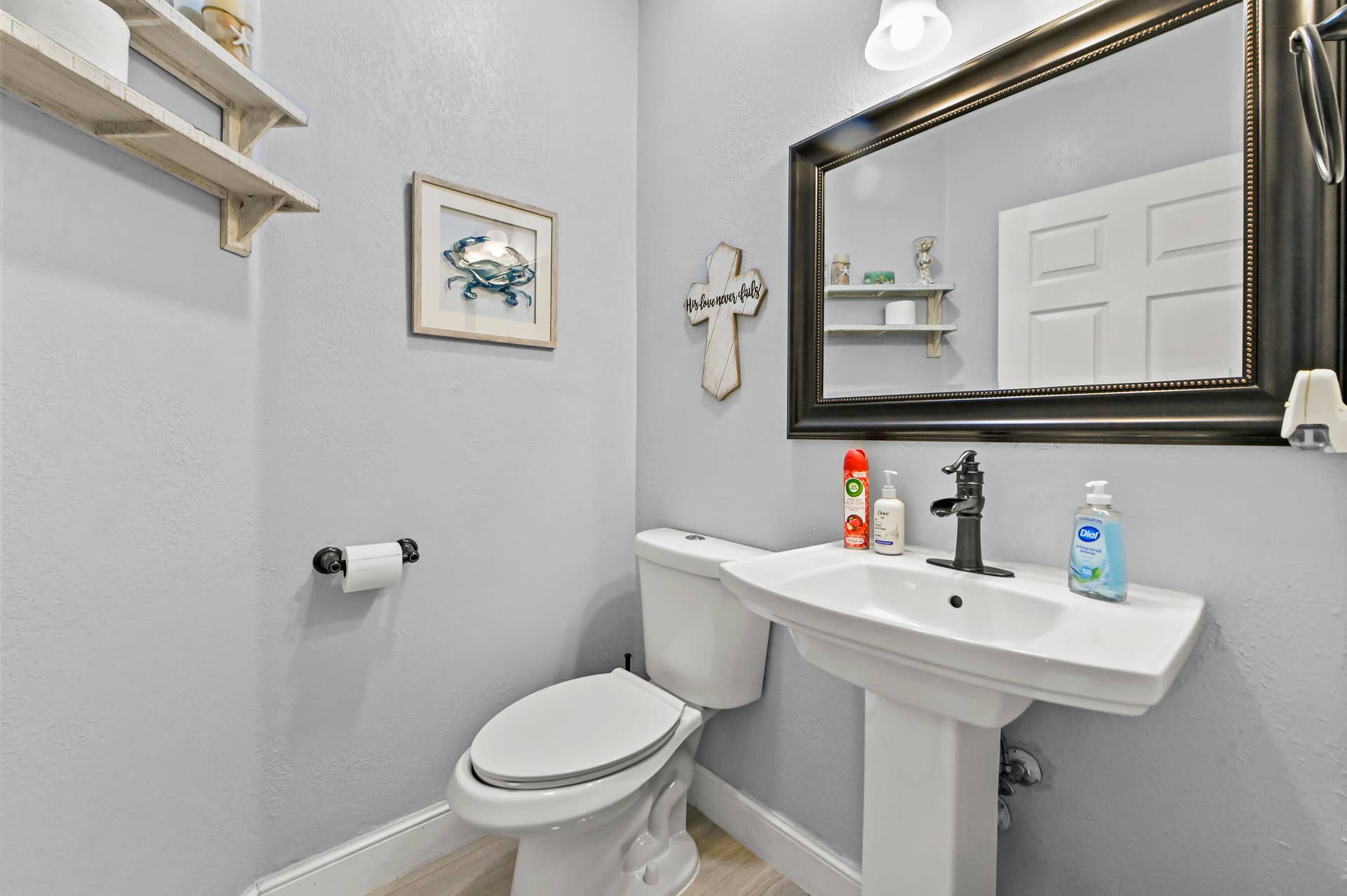 Pedestal sink with a single-handle faucet, wall-mounted mirror, and overhead lighting