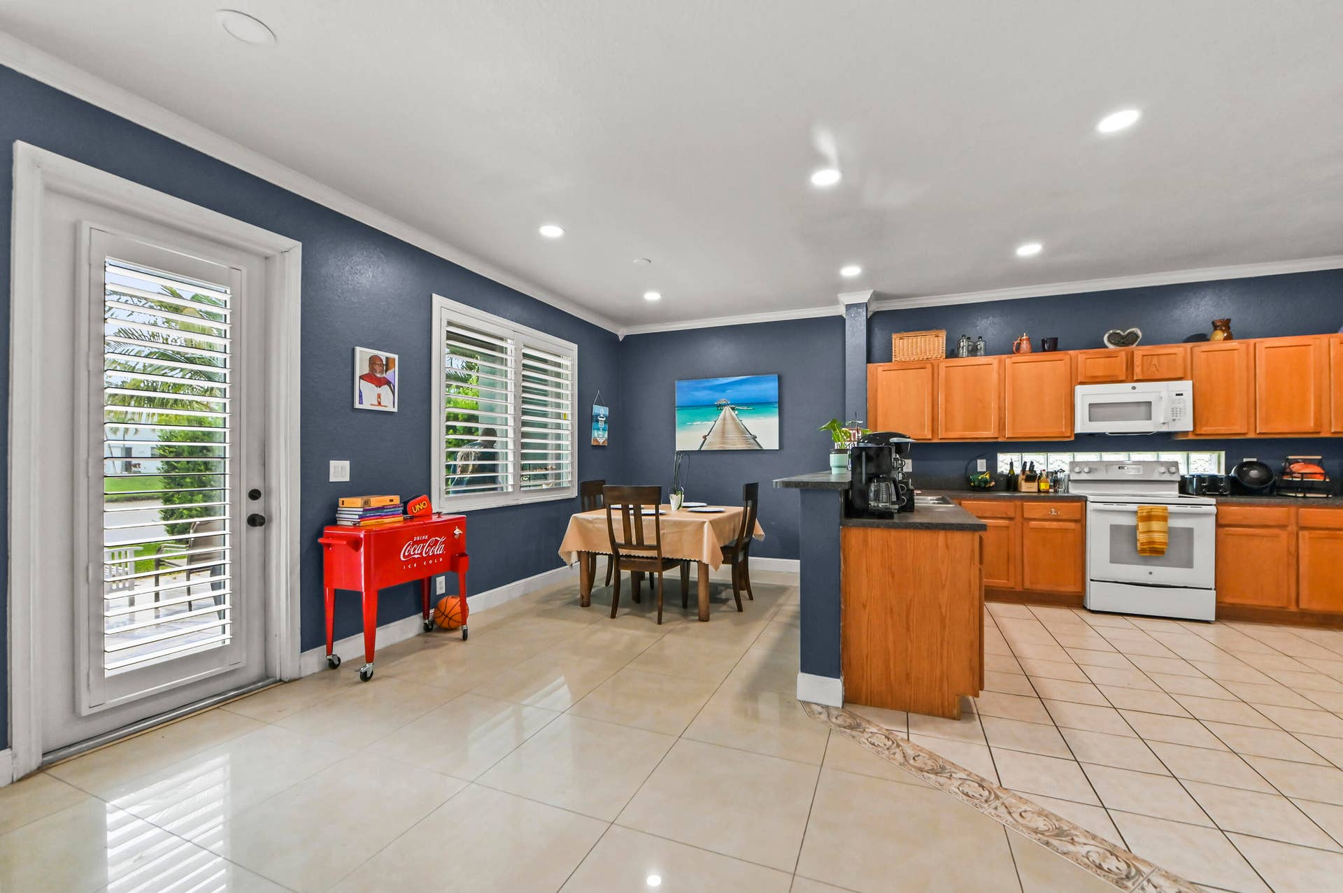 Spacious kitchen featuring light wood cabinetry, white appliances, and a breakfast bar