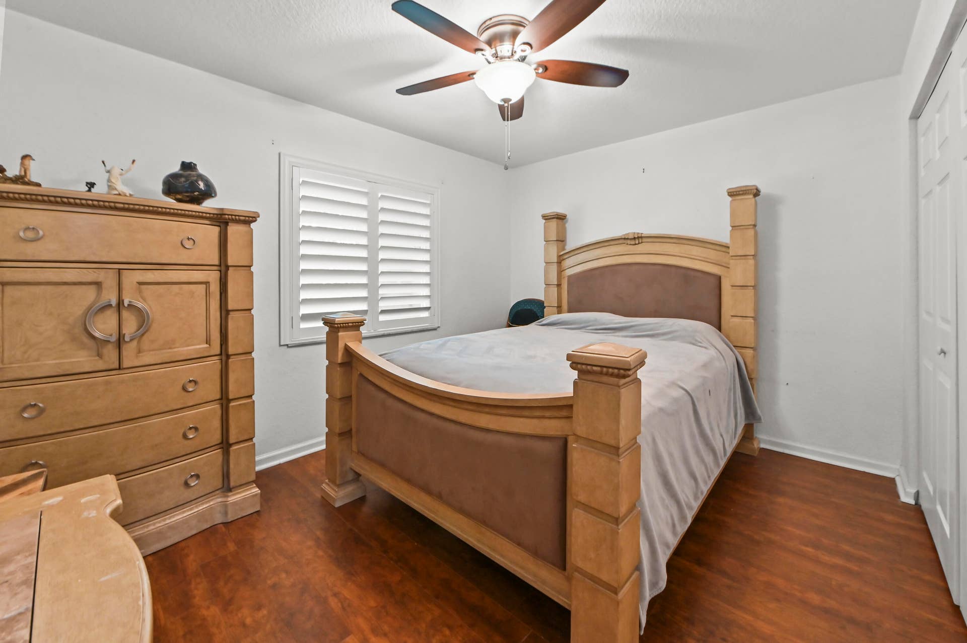 Wood-finish flooring, ceiling fan with integrated lighting, and white plantation shutters