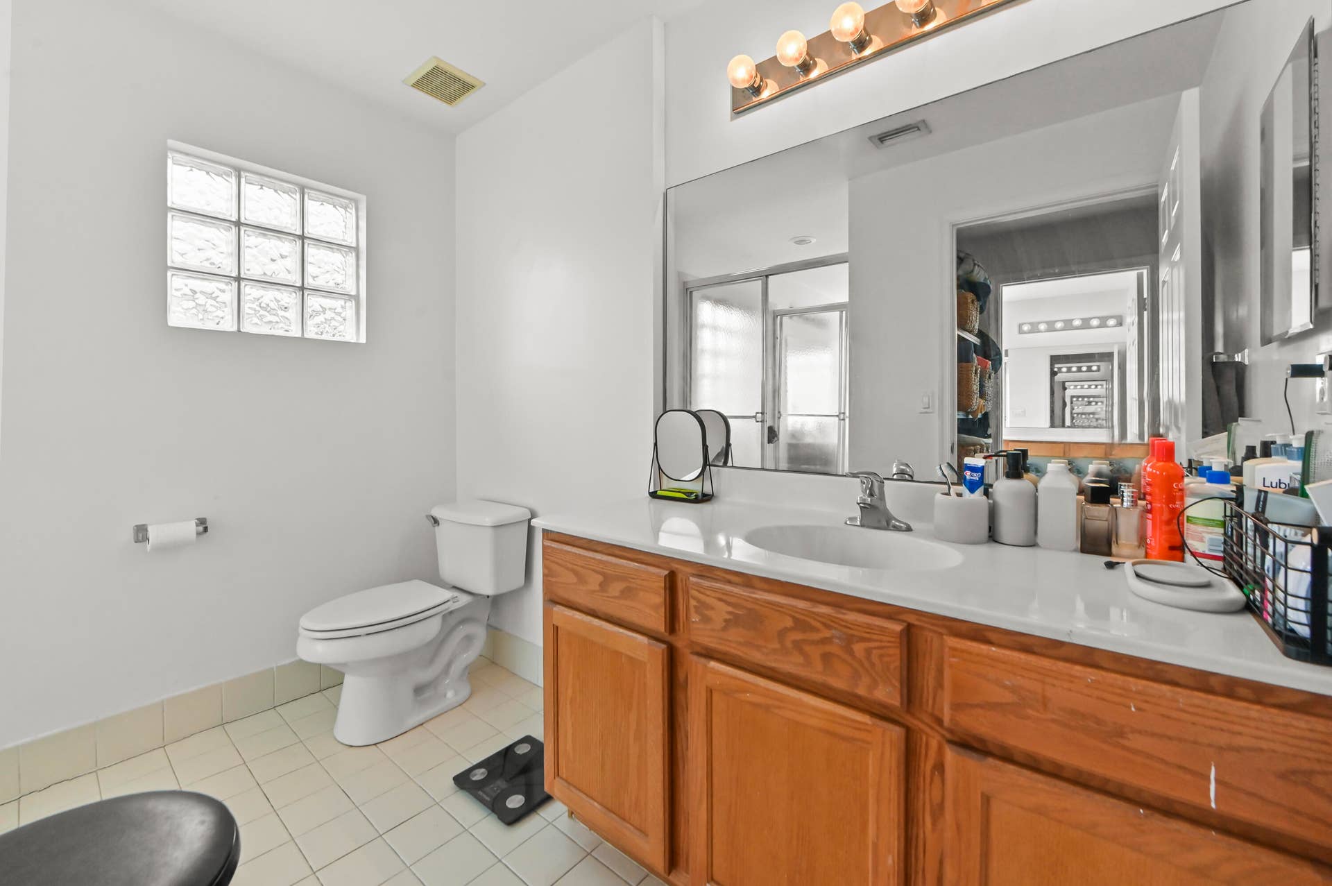 Single vanity with wood-finish cabinetry, integrated sink, and extended mirror