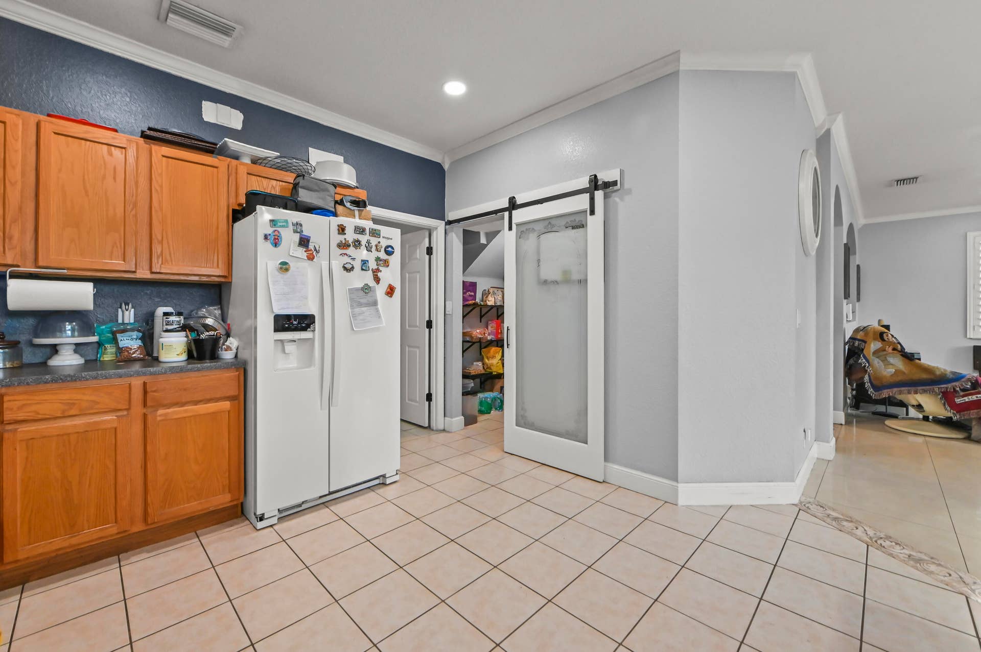 Kitchen featuring wood-finish cabinetry, tile flooring, recessed lighting, and a barn-style door