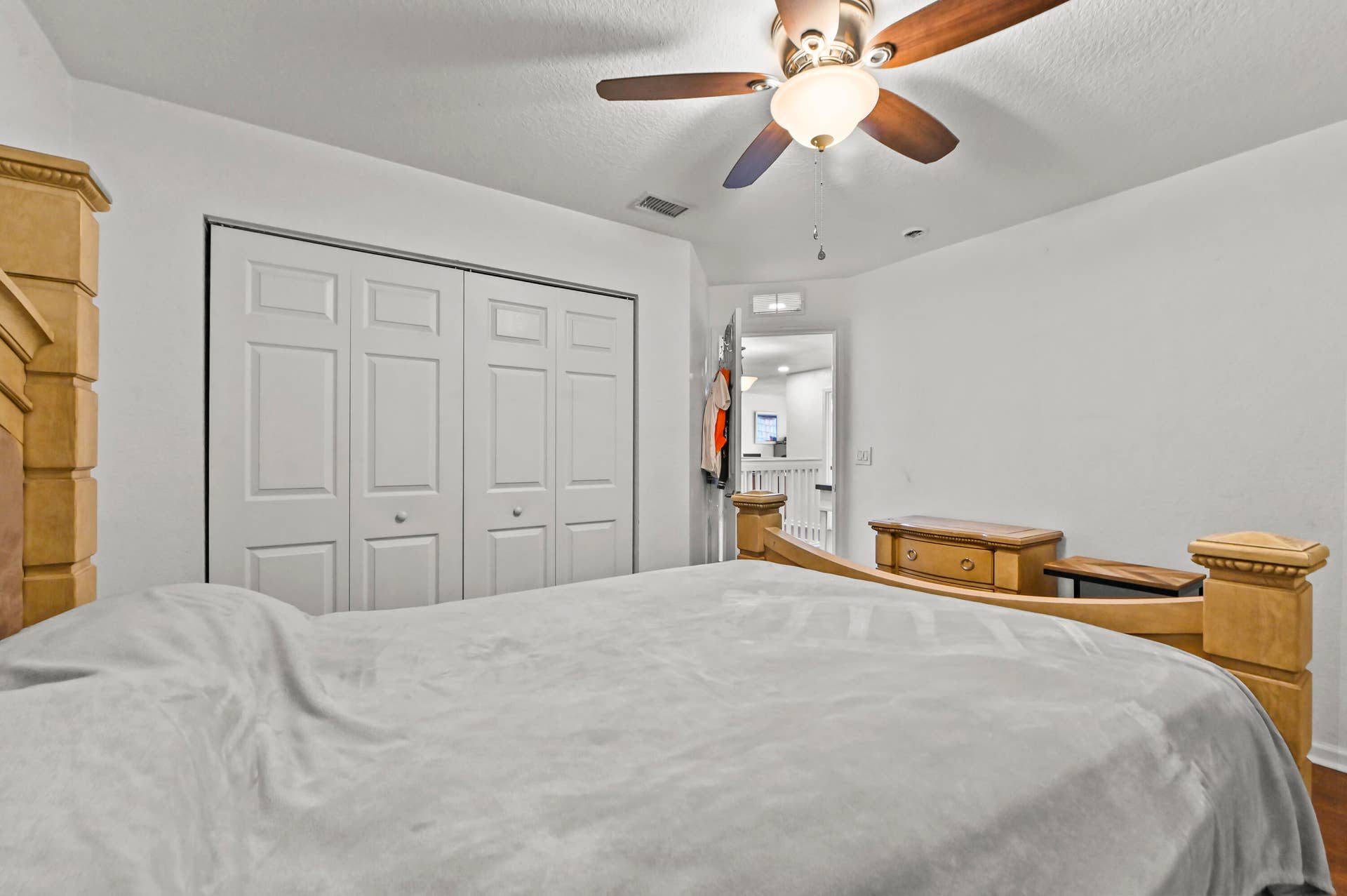 Ceiling fan with light fixture, double bi-fold closet doors, white wall finishes, wood-finish flooring
