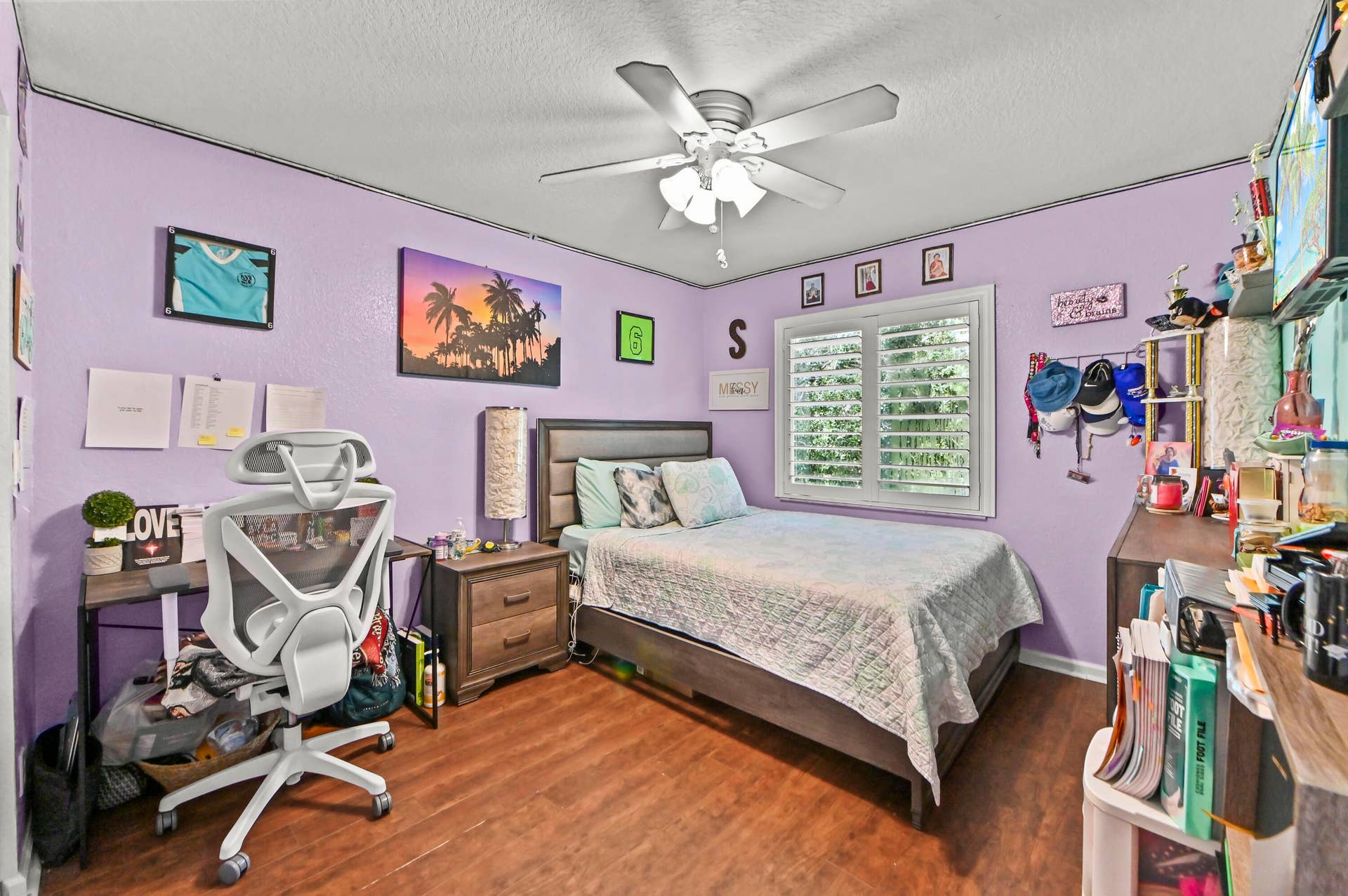 Bright bedroom featuring lavender walls, wood-finish flooring, and a ceiling fan with integrated lighting