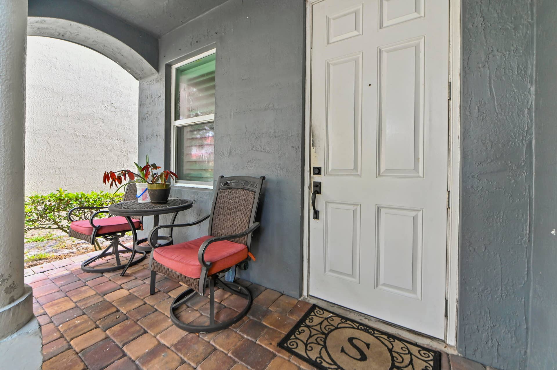 Entry porch with brick paver flooring and a paneled white door