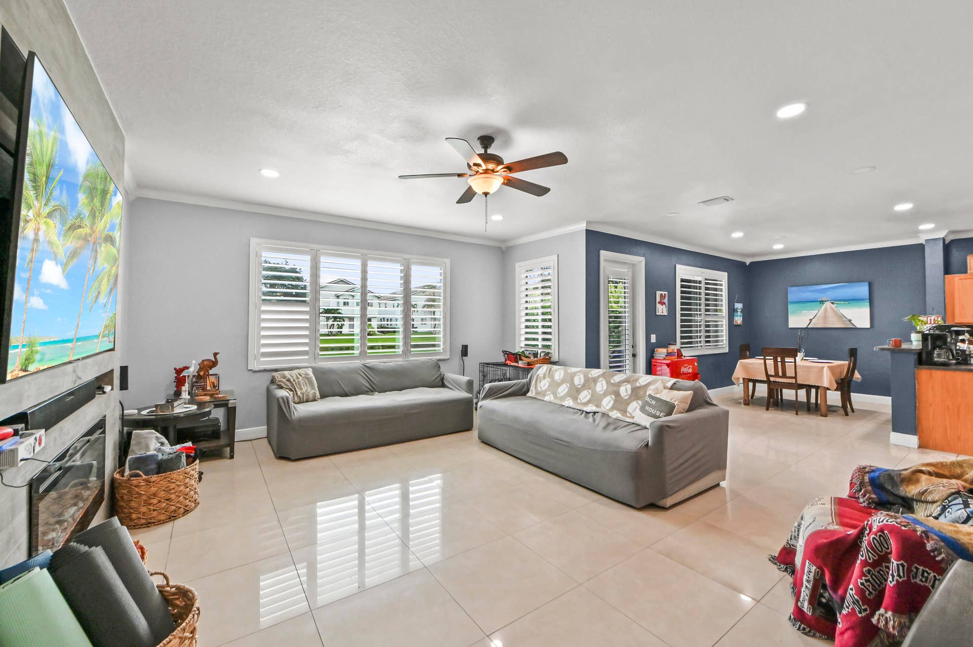 Spacious open-concept living area featuring large format tile flooring, crown molding, and recessed lighting