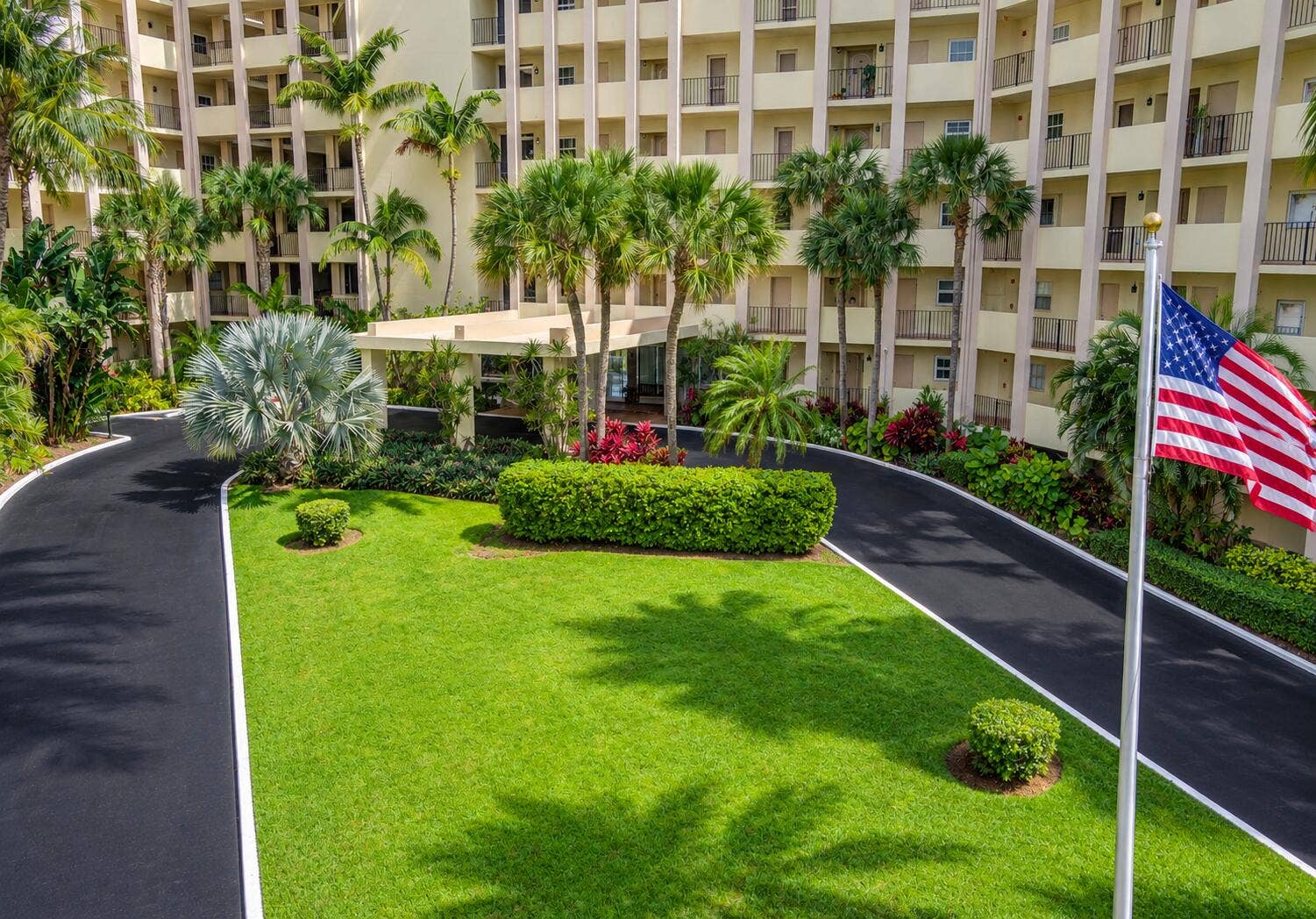 3475 S OCEAN Boulevard, #2050, Palm Beach, FL 33480 Multi-story building exterior with individual balconies, lush landscaping, mature palm trees, and a paved driveway