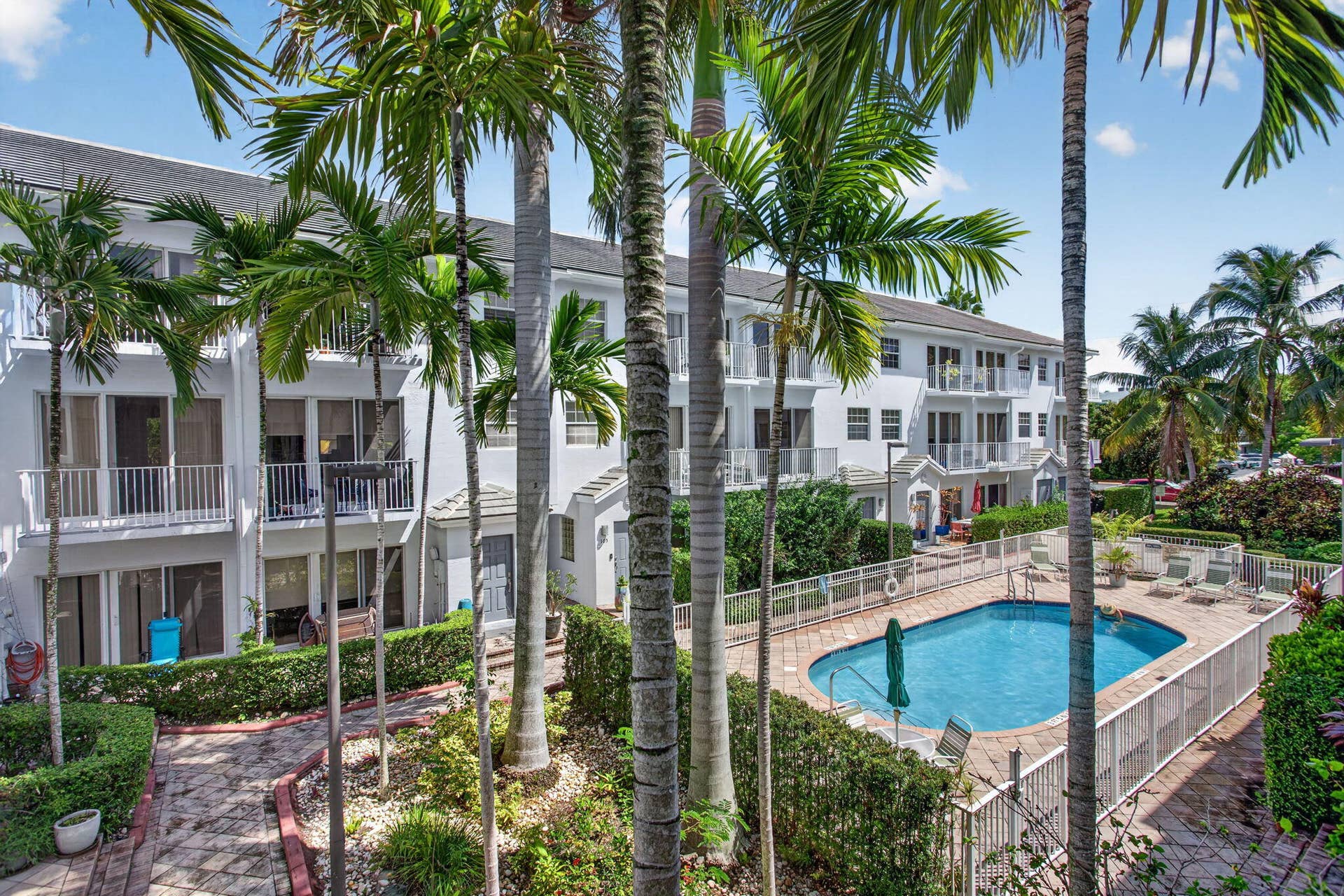 2725 NE 8TH Avenue, #112, Wilton Manors, FL 33334 Two-story residences with balconies, a swimming pool with paved decking, and lush landscaping