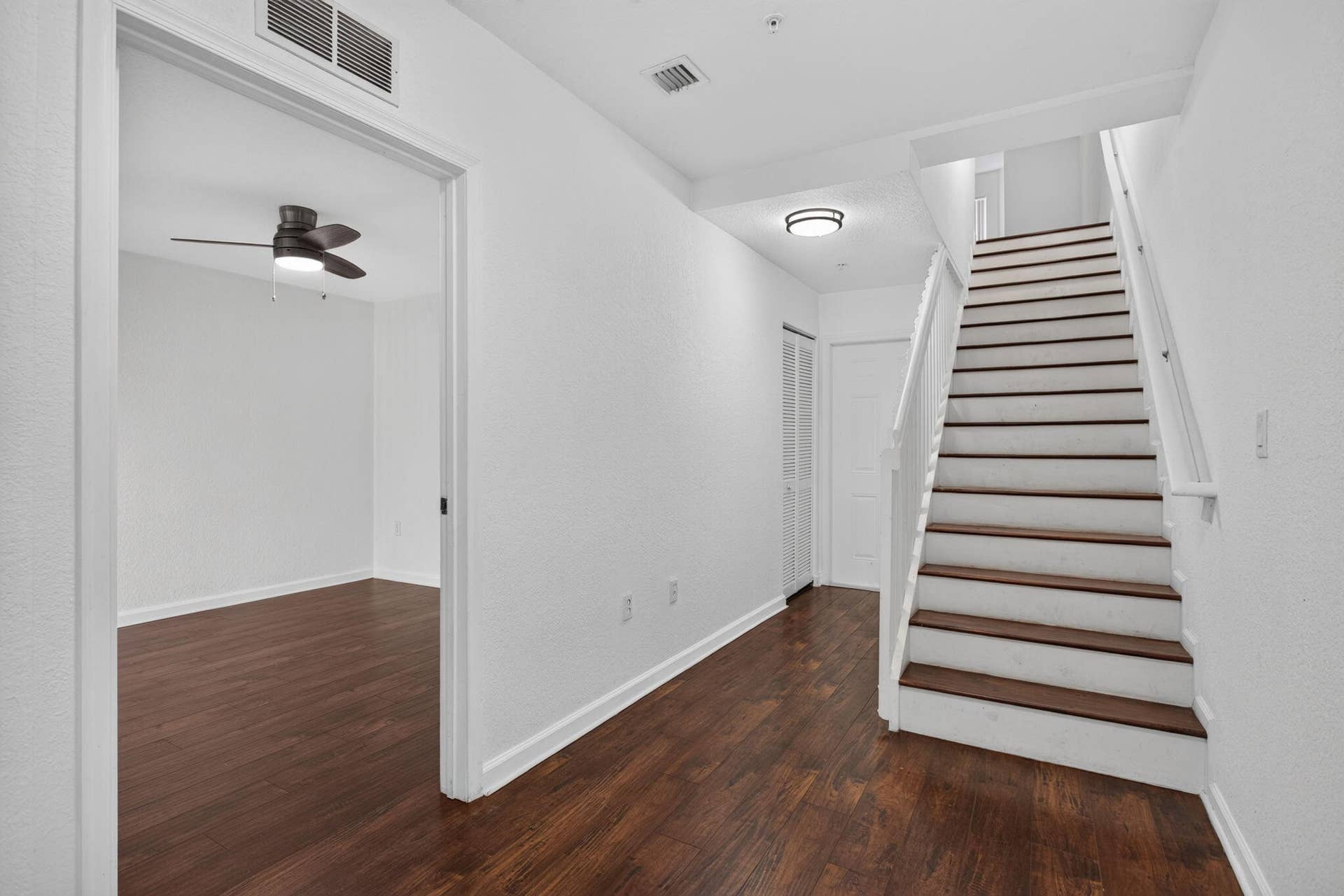 2725 NE 8TH Avenue, #112, Wilton Manors, FL 33334 Wood-finish flooring throughout, white walls, and a staircase with white risers and dark wood treads
