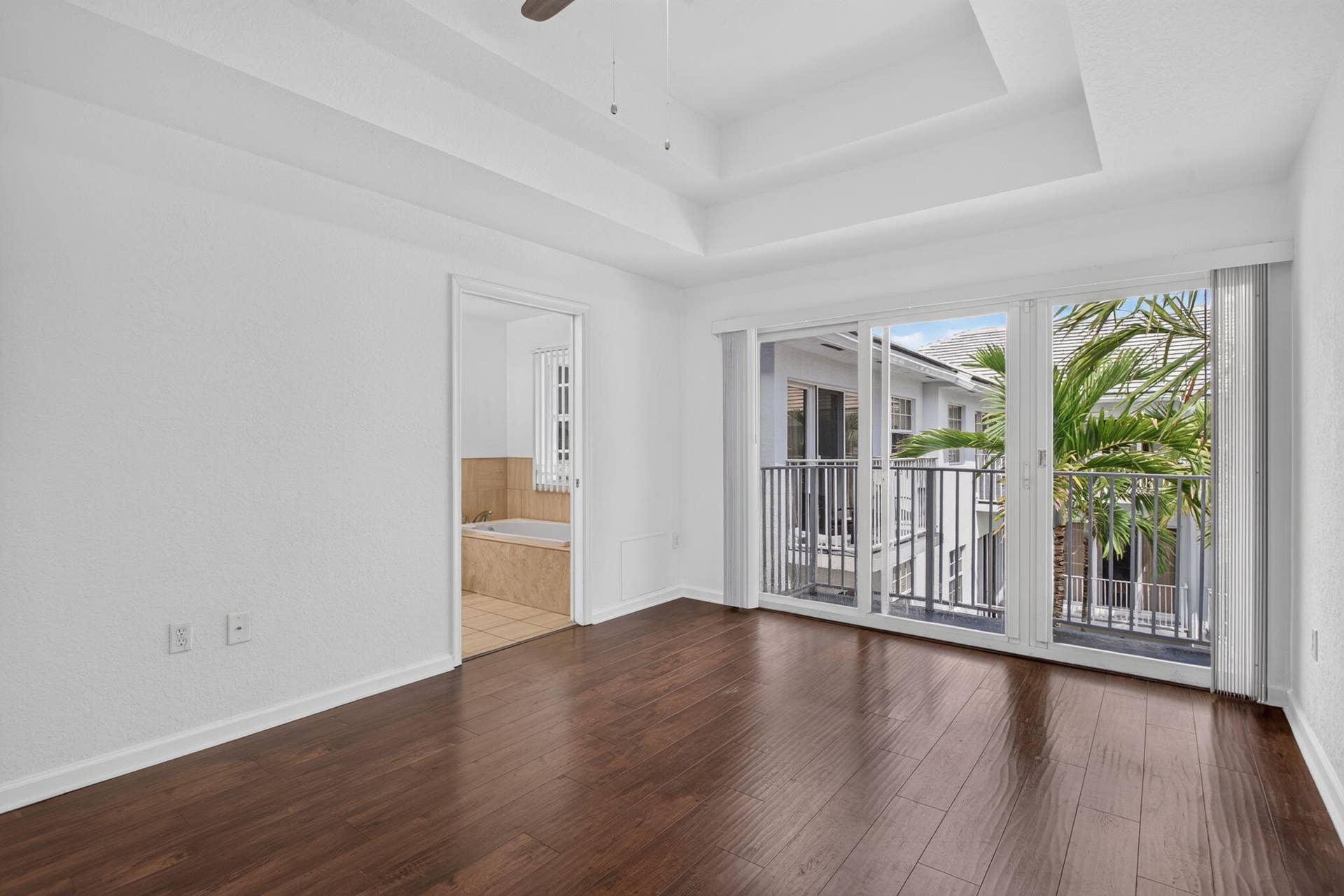 2725 NE 8TH Avenue, #112, Wilton Manors, FL 33334 Tray ceiling, wood-finish flooring, sliding glass door, private balcony with black railings, and a built-in tub