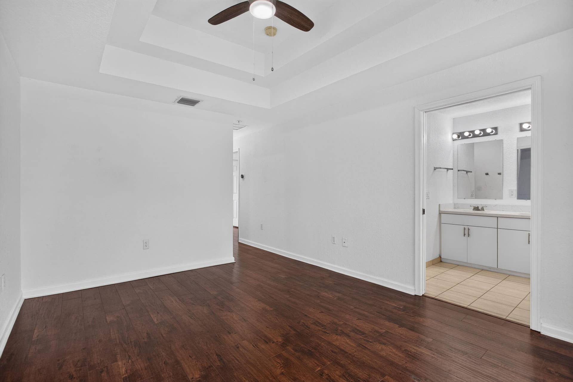 2725 NE 8TH Avenue, #112, Wilton Manors, FL 33334 Wood-finish flooring, tray ceiling, ceiling fan, and an en-suite bathroom featuring a double vanity with an integrated mirror