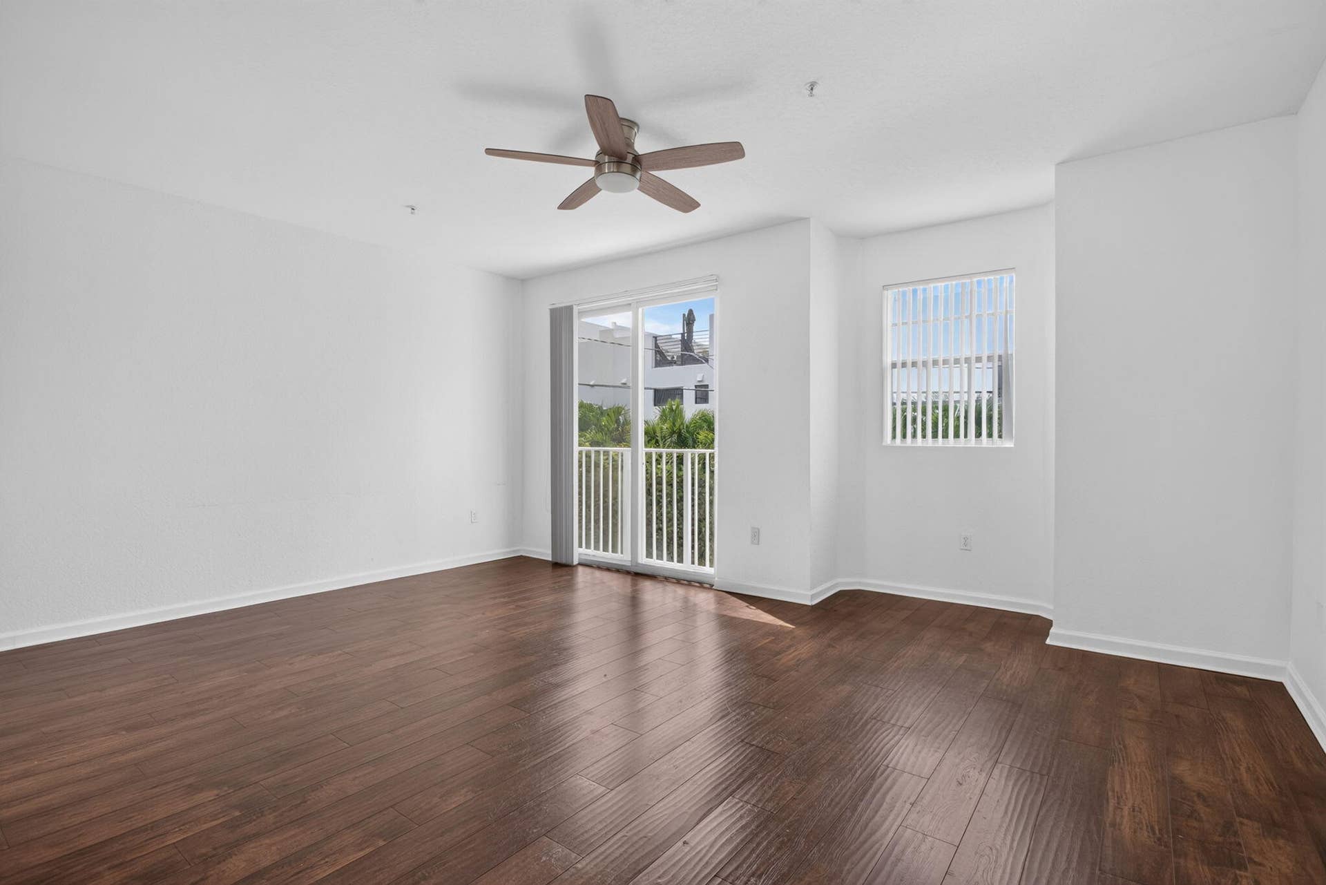 2725 NE 8TH Avenue, #112, Wilton Manors, FL 33334 Hardwood-finish flooring, ceiling fan, sliding glass door with balcony access, and a window with blinds