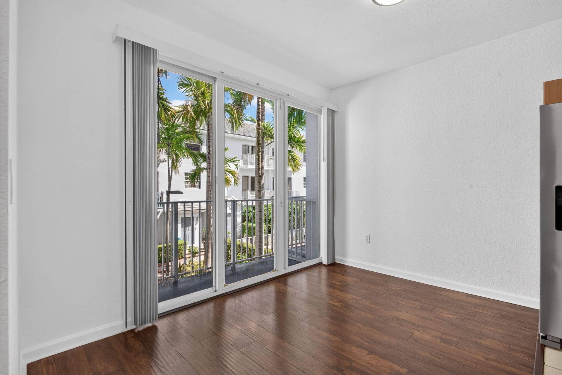 2725 NE 8TH Avenue, #112, Wilton Manors, FL 33334 Wood-finish flooring with floor-to-ceiling sliding glass doors opening to a balcony with metal railings