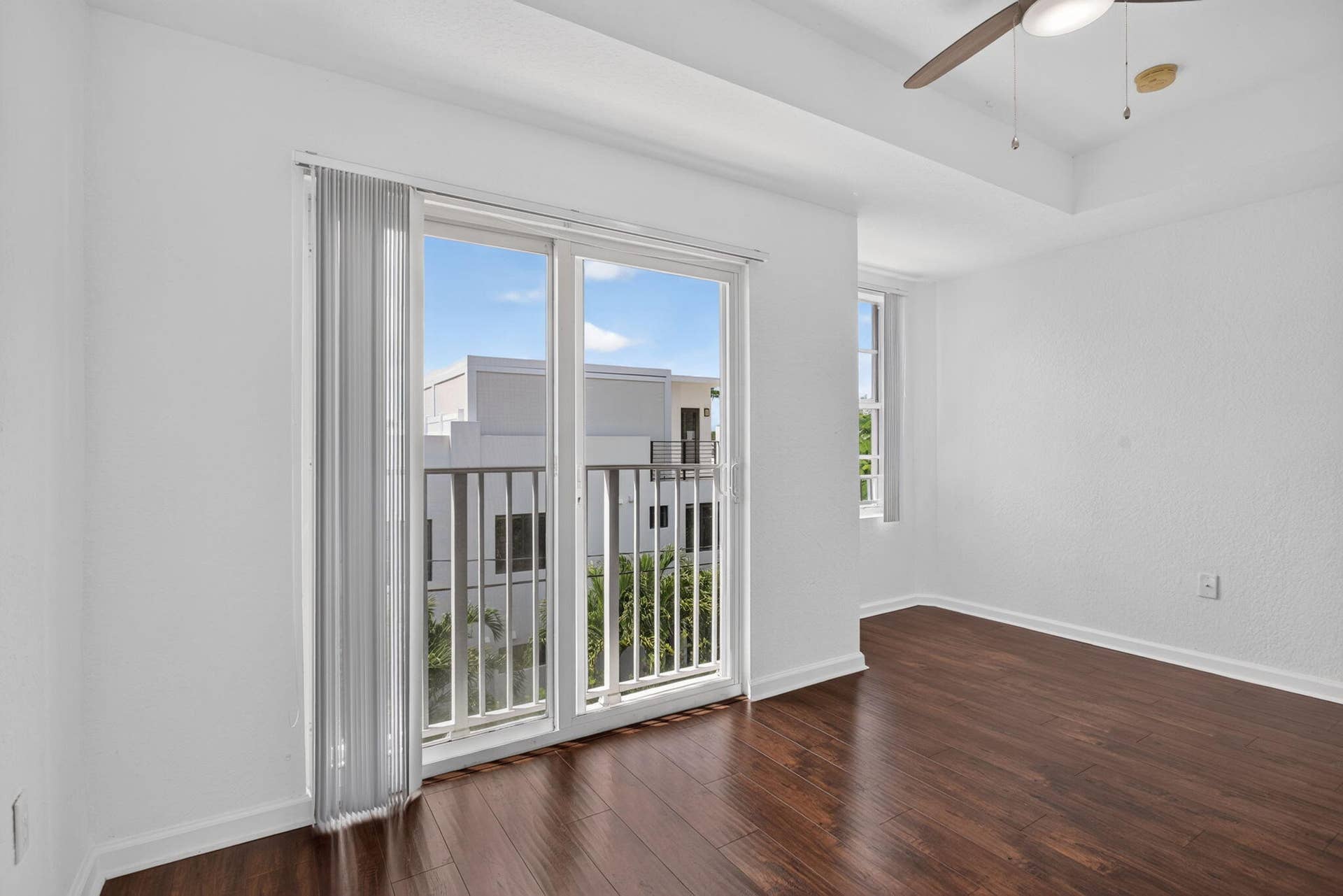 2725 NE 8TH Avenue, #112, Wilton Manors, FL 33334 Balcony access with a sliding glass door, wood-finish flooring, a ceiling fan, and a tray ceiling