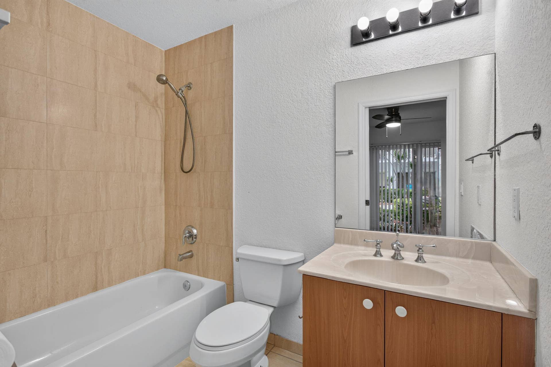 2725 NE 8TH Avenue, #112, Wilton Manors, FL 33334 Bathroom featuring a tub/shower combination with light-toned wall tiling, a vanity with a light-colored countertop, and a built-in wood-finish cabinet