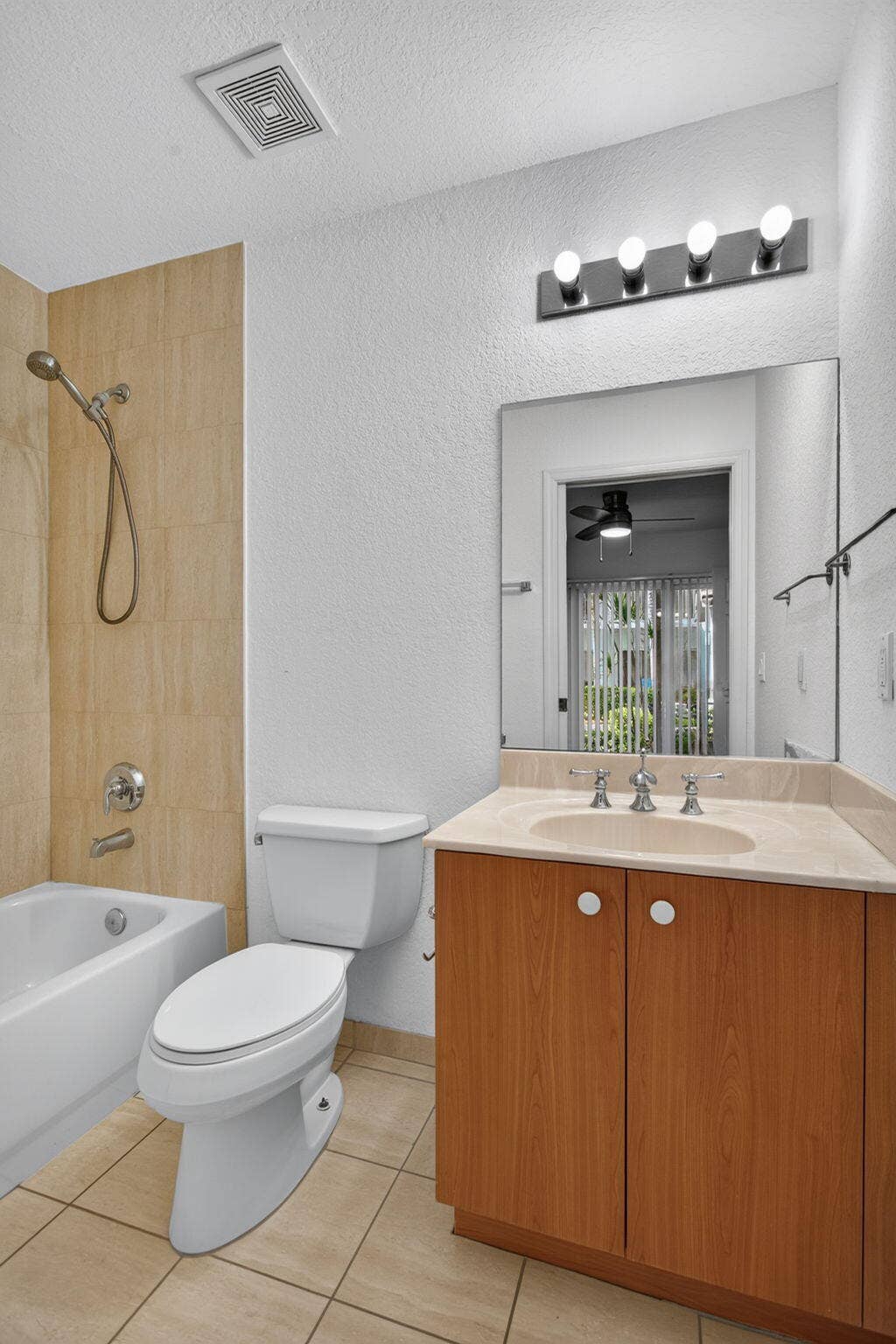 2725 NE 8TH Avenue, #112, Wilton Manors, FL 33334 Tiled shower with handheld shower fixture, light wood-finish vanity, light-colored countertop, and a vanity mirror