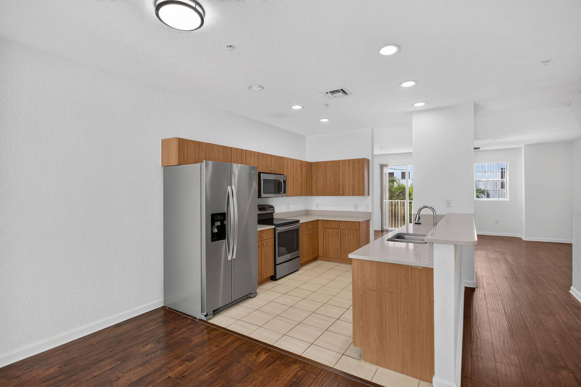 2725 NE 8TH Avenue, #112, Wilton Manors, FL 33334 Kitchen featuring wood-finish cabinetry, stainless steel appliances, and light-toned countertops