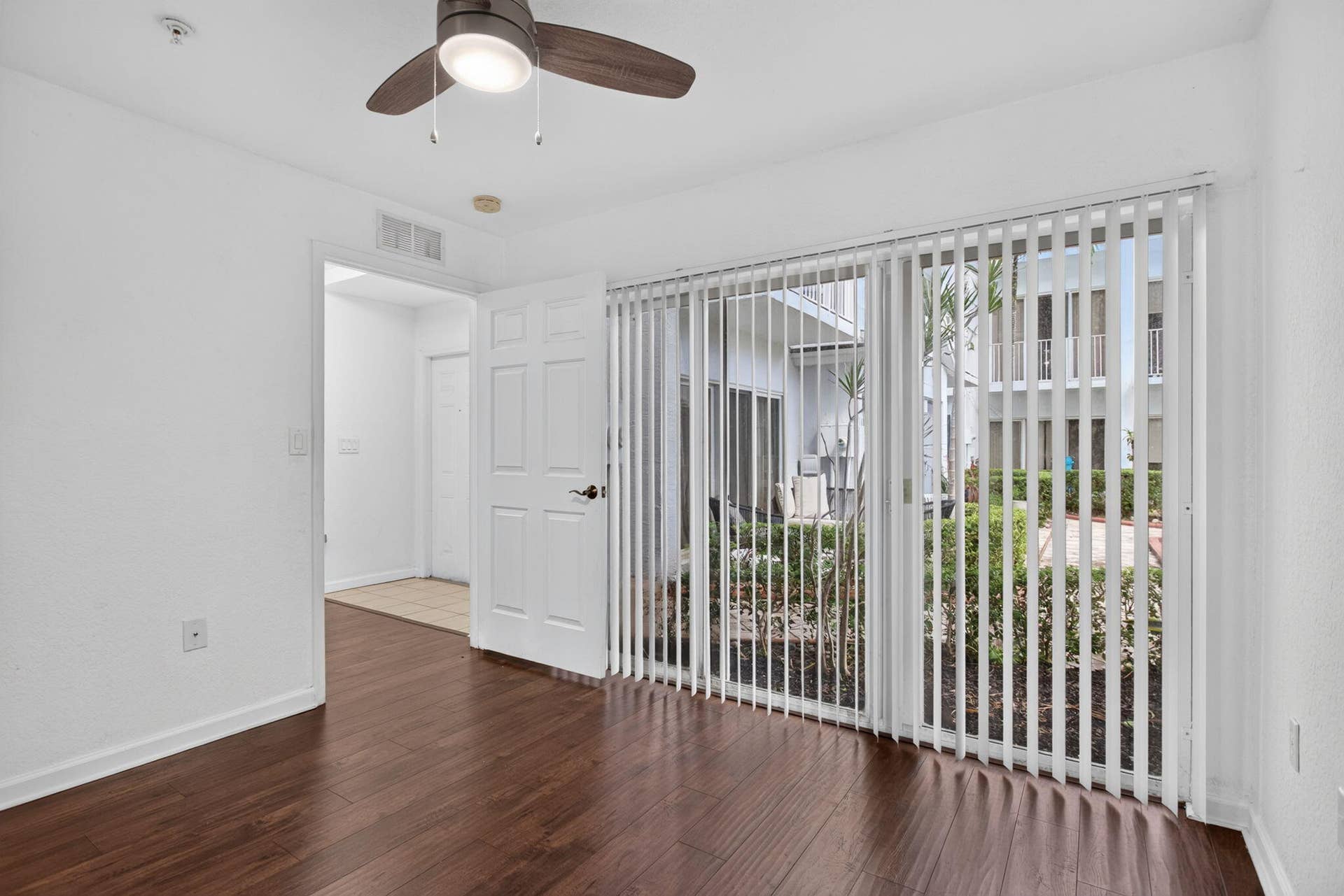 2725 NE 8TH Avenue, #112, Wilton Manors, FL 33334 Wood-finish flooring, ceiling fan with integrated lighting, and full-height vertical blinds