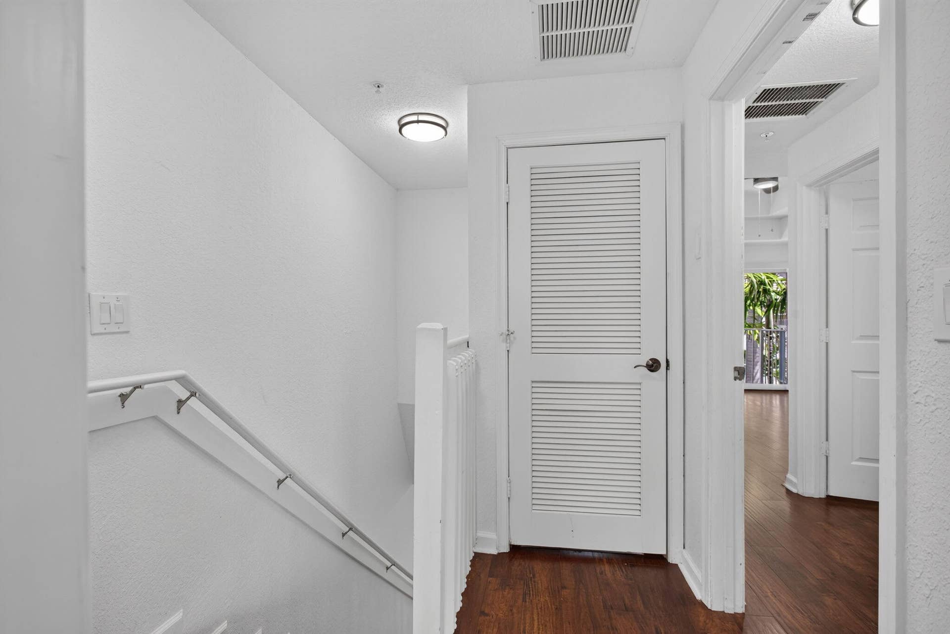 2725 NE 8TH Avenue, #112, Wilton Manors, FL 33334 Hallway featuring wood-finish flooring, white louvered door, white painted walls, and ceiling-mounted lighting