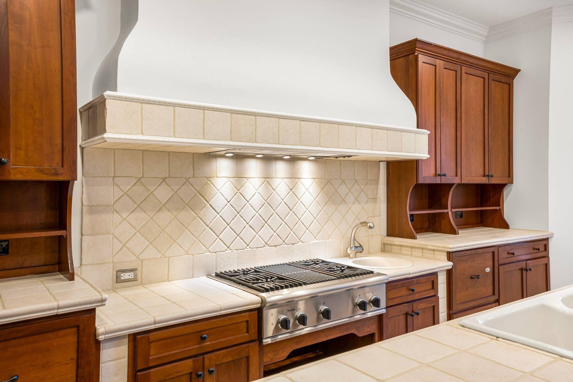 CUSTOM RANGE HOOD CREATES A STRIKING POINT OVER THE GAS COOKTOP