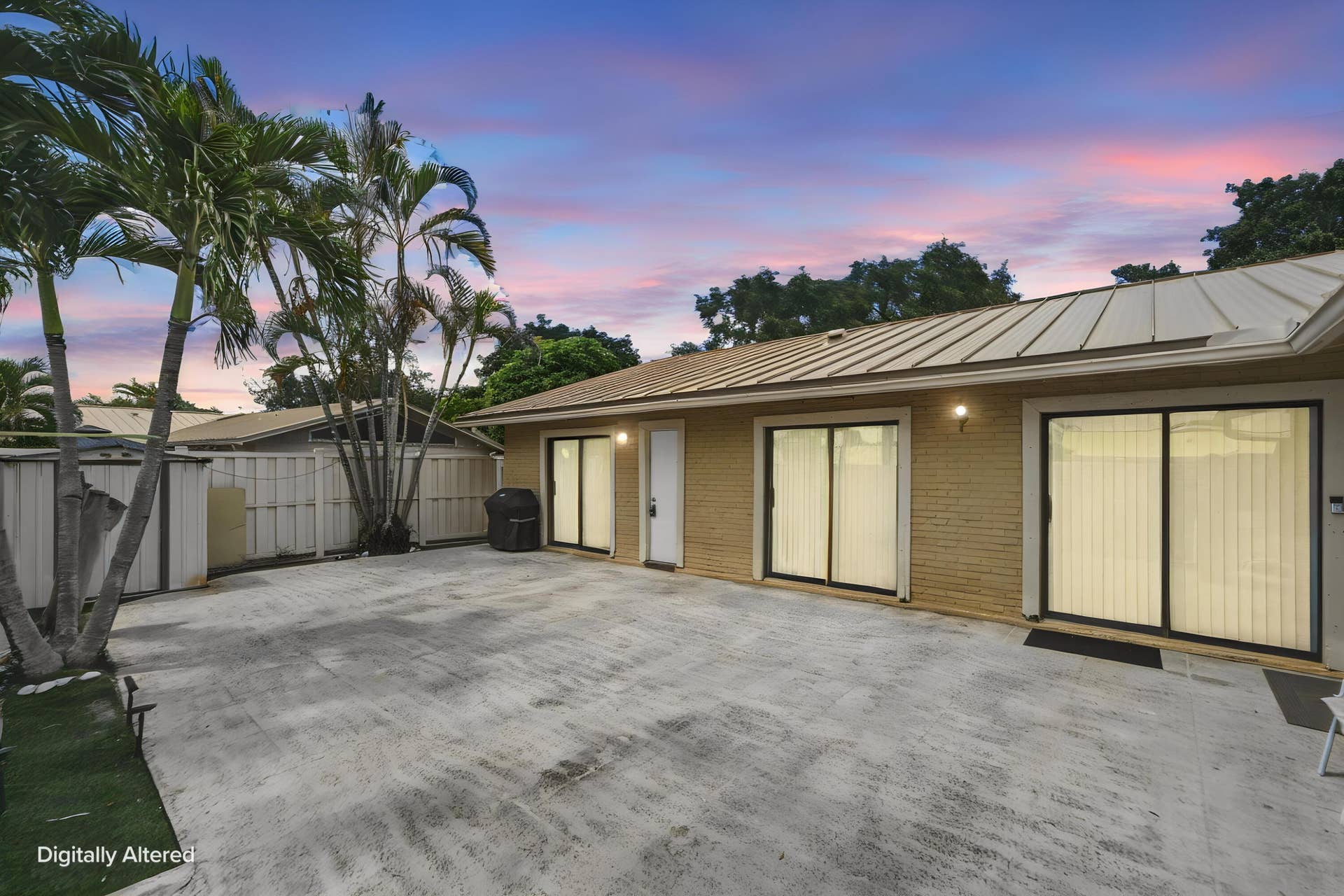 Expansive concrete patio with multiple sliding glass doors, a metal seam roof, and established palm trees
