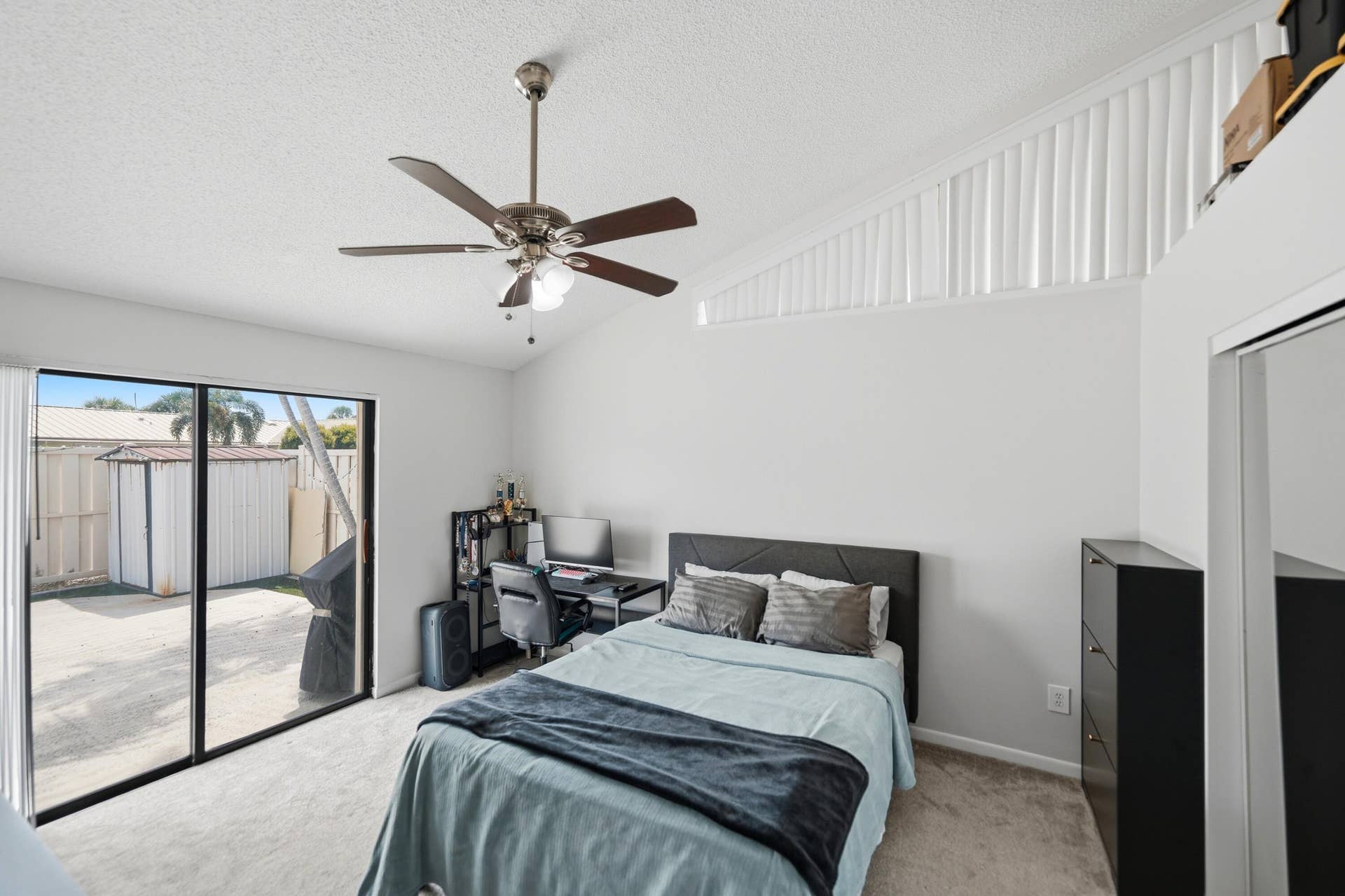 Vaulted ceiling with a ceiling fan, sliding glass door, and wall-to-wall carpeting