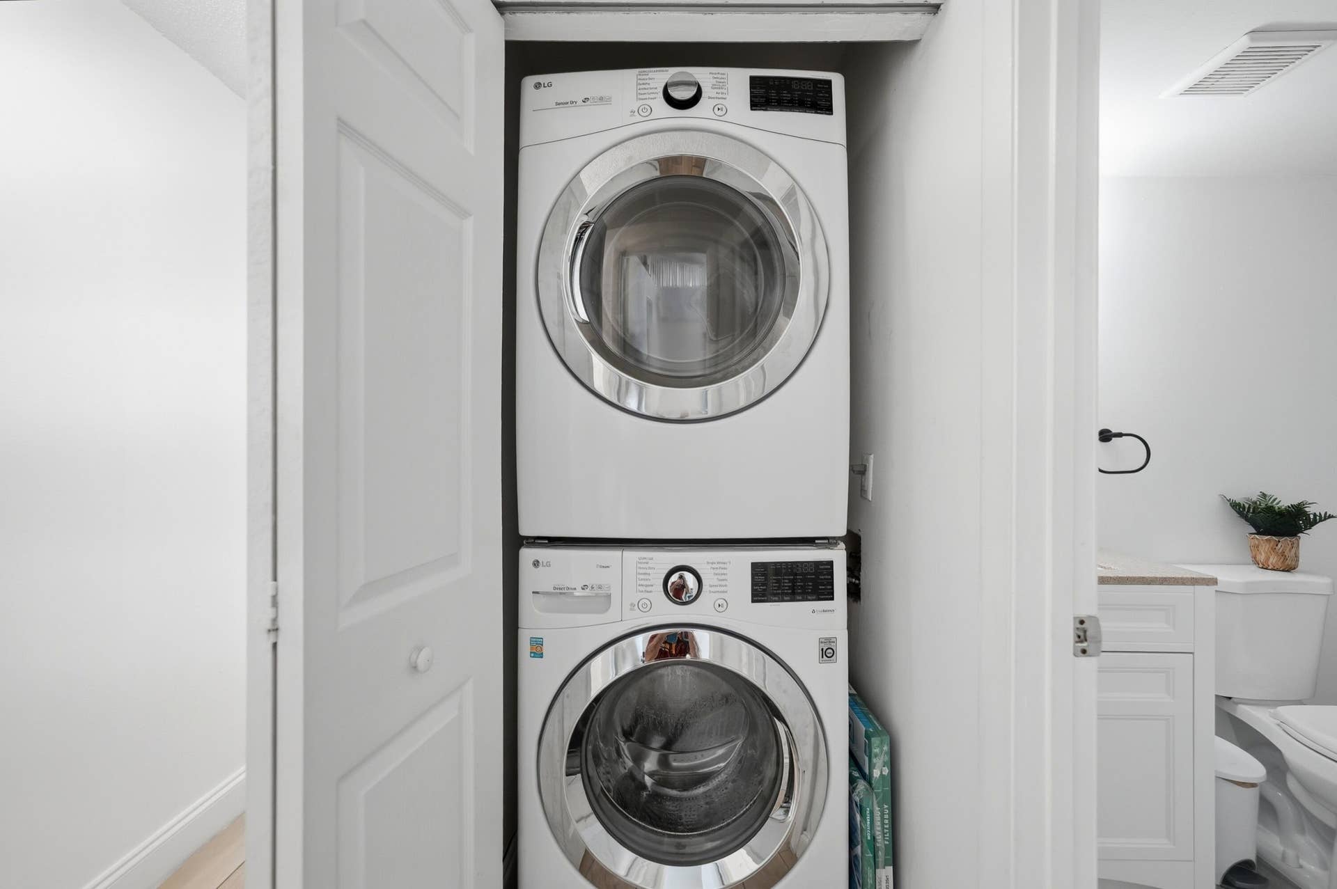 Stackable white front-load washer and dryer within a dedicated closet
