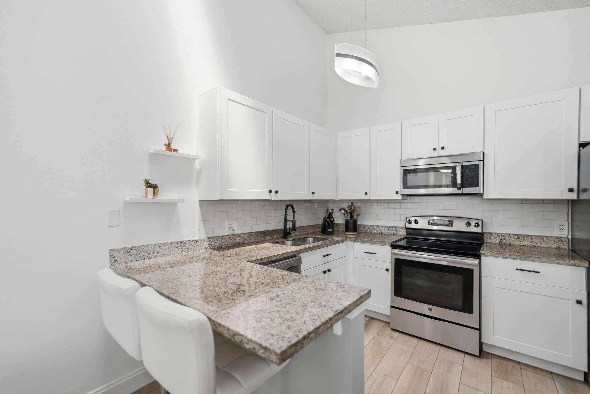 Kitchen featuring white cabinetry, stainless steel appliances, granite countertops, and a subway tile backsplash