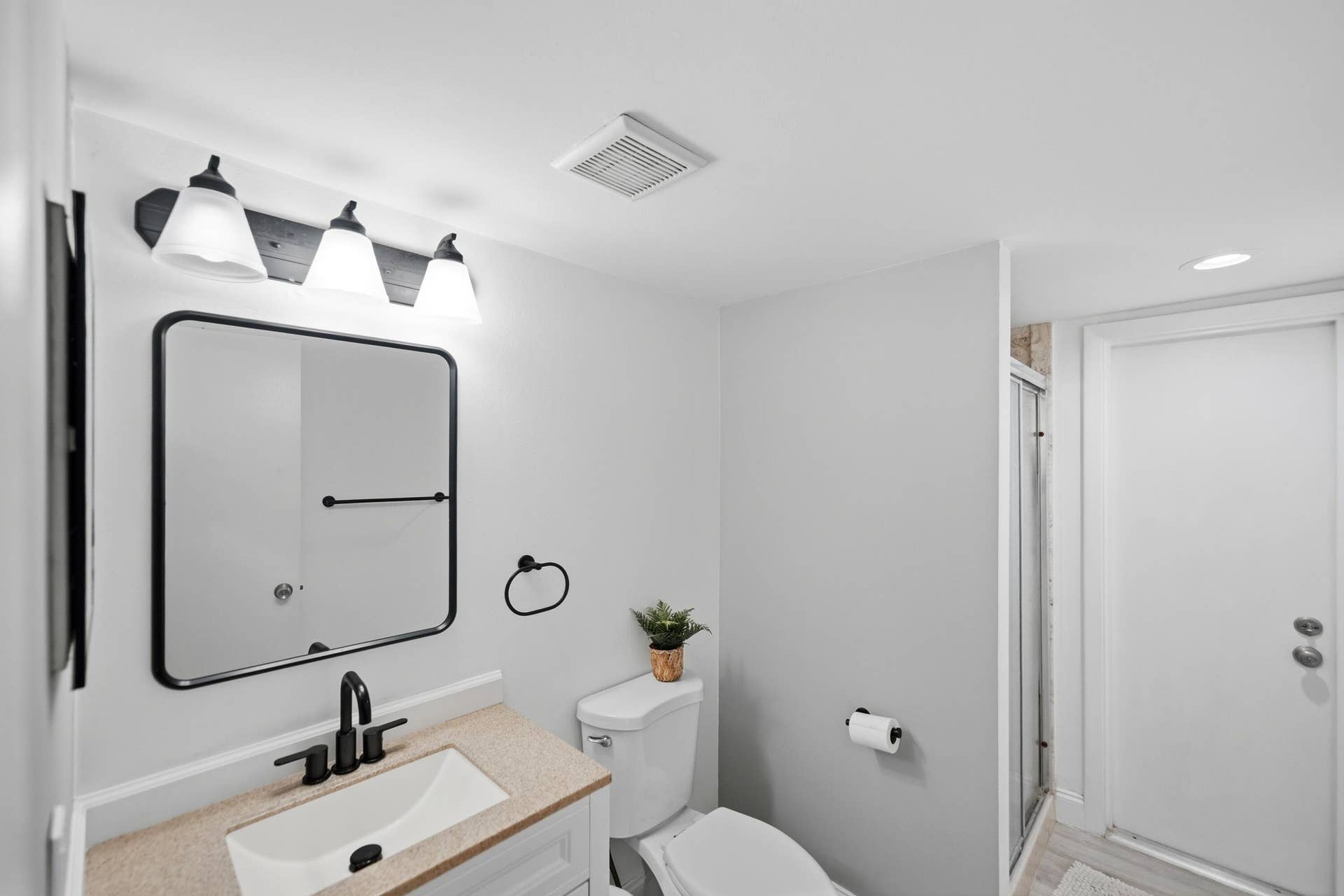 Vanity with light-toned countertop, rectangular undermount sink, and matte black faucet