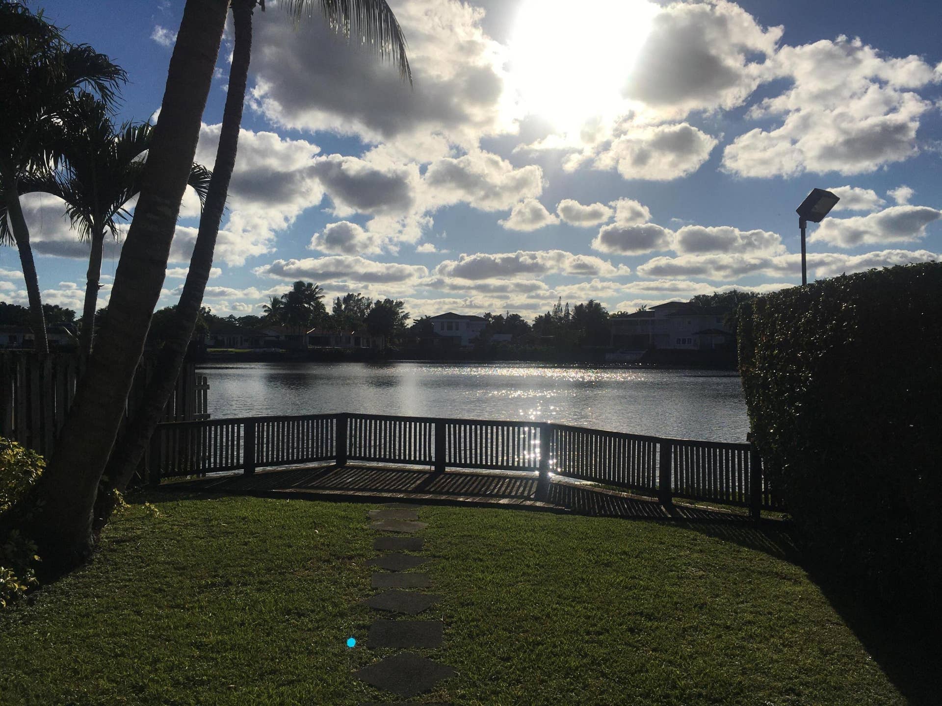 2390 NE 199th Street, Aventura, FL 33180 Expansive waterfront property featuring a wooden deck, mature palm trees, and a manicured lawn