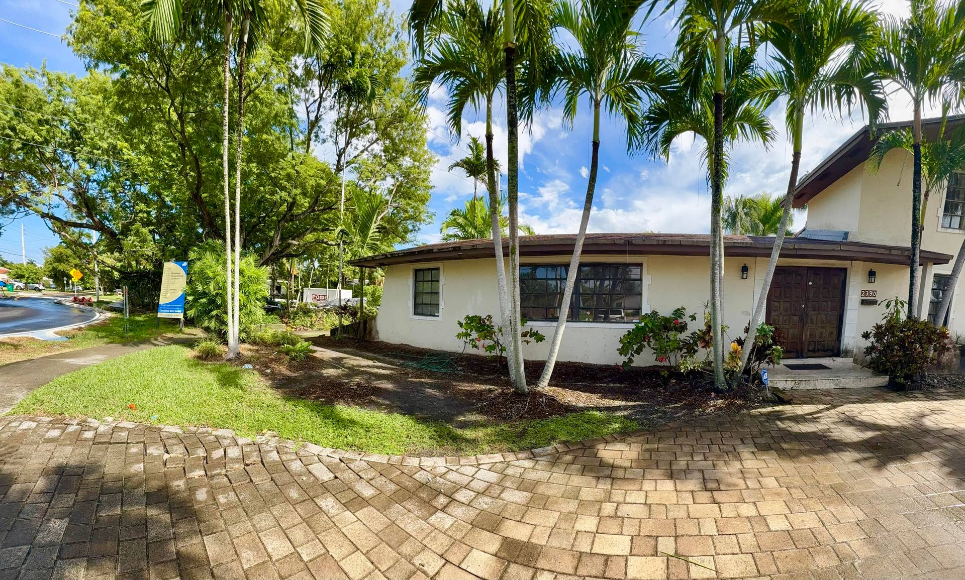 2390 NE 199th Street, Aventura, FL 33180 Stucco exterior with a tiled roof, mature palm trees, decorative front doors, and a paver driveway
