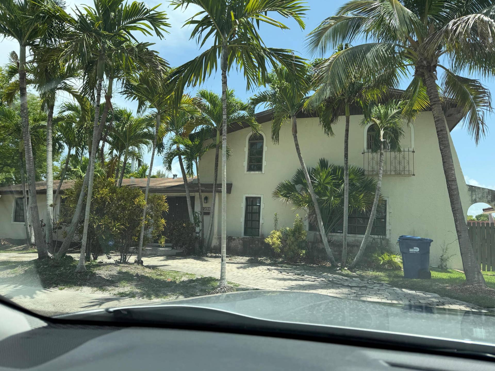 2390 NE 199th Street, Aventura, FL 33180 Stucco exterior with arched windows, wrought iron balcony, and mature palm trees