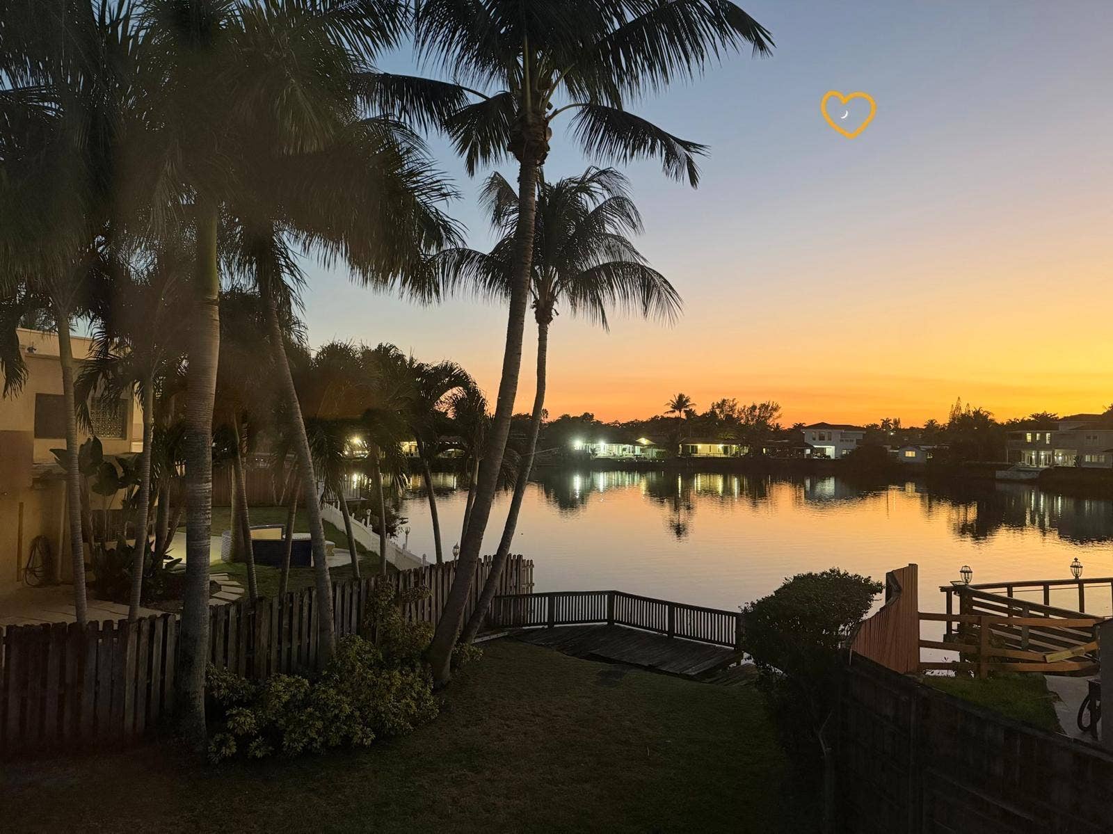 2390 NE 199th Street, Aventura, FL 33180 Waterfront property featuring a private boat dock, wood fencing, and mature palm trees