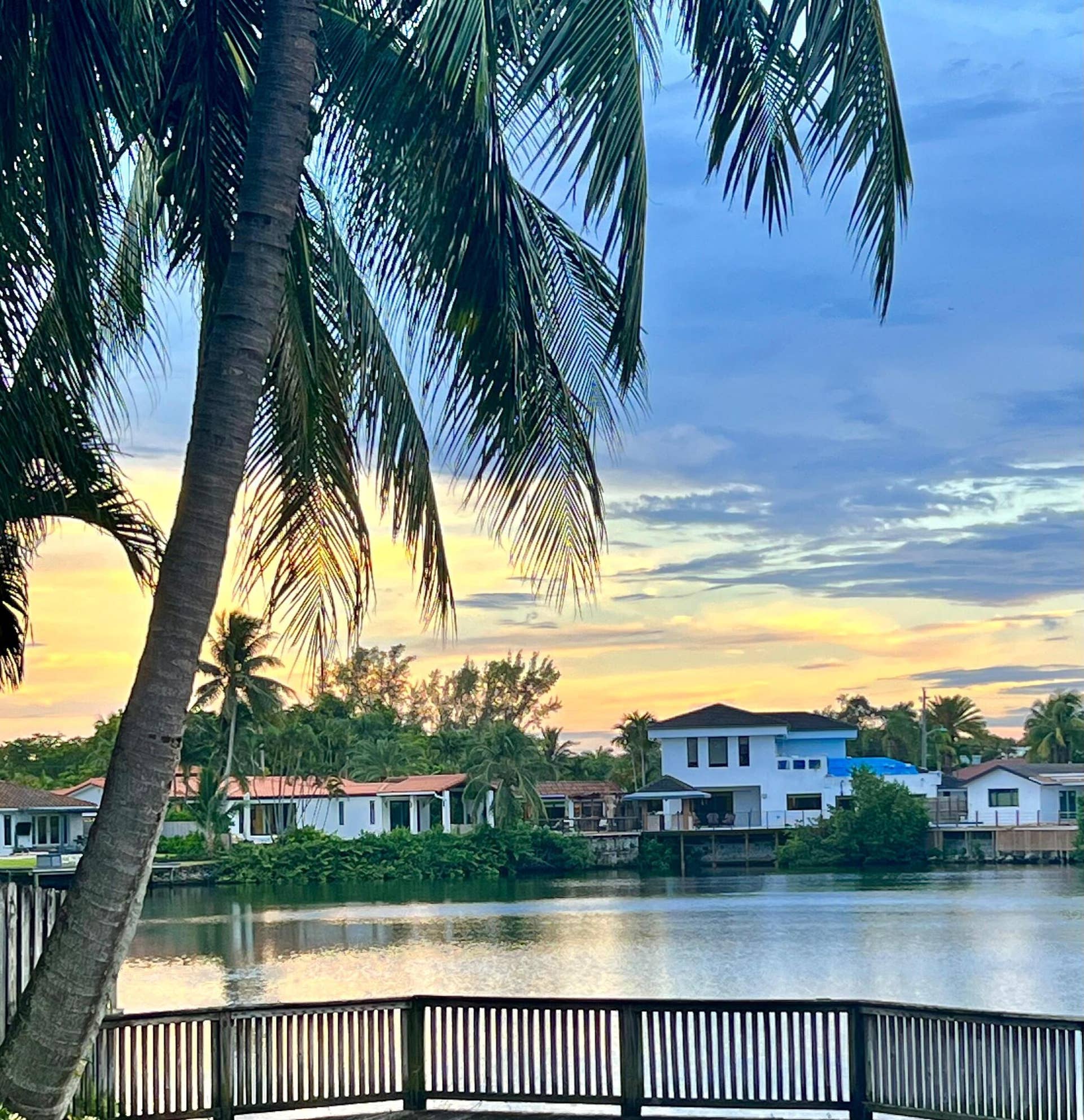 2390 NE 199th Street, Aventura, FL 33180 Waterfront property featuring a wood-finish railing, water frontage, and lush palm trees