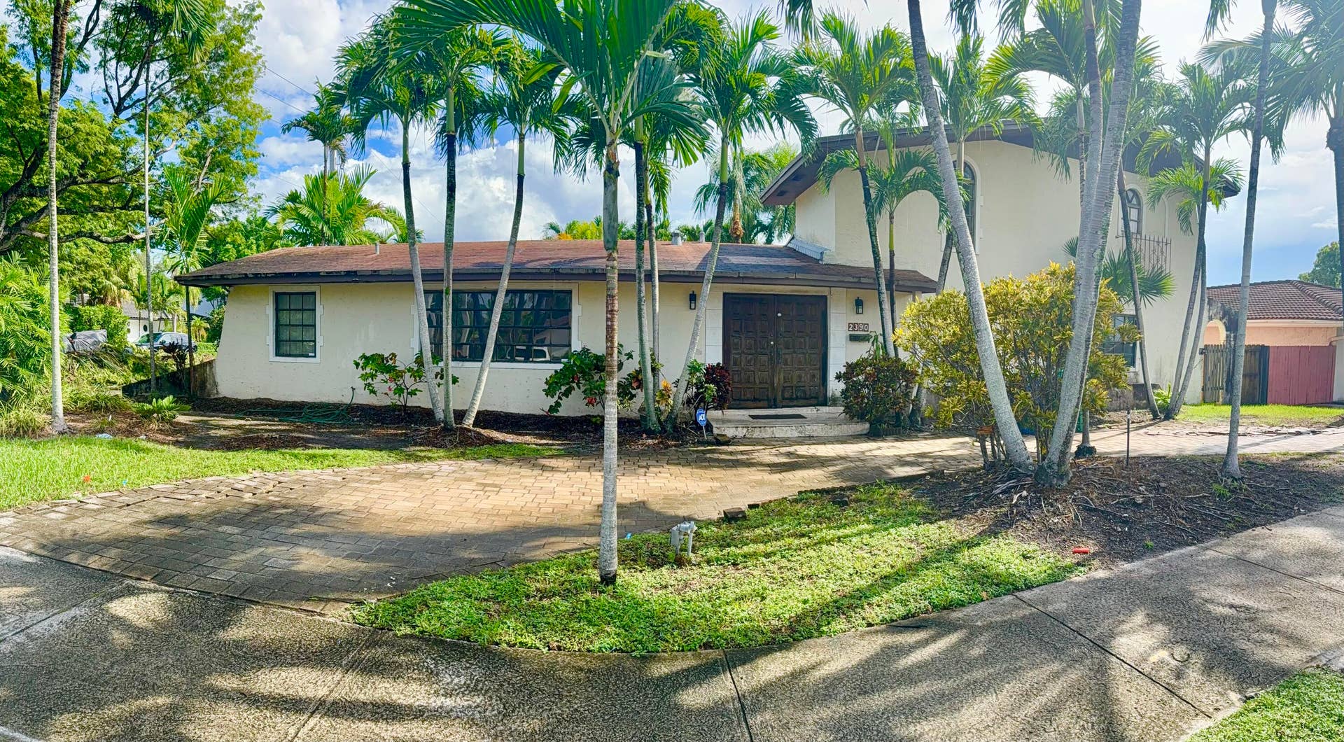 2390 NE 199th Street, Aventura, FL 33180 Stucco exterior residence with a brown roof, multiple windows, and a double-door entry