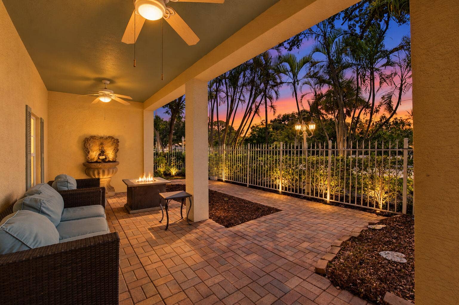 Covered patio with a paver floor, two ceiling fans, and a built-in fire pit