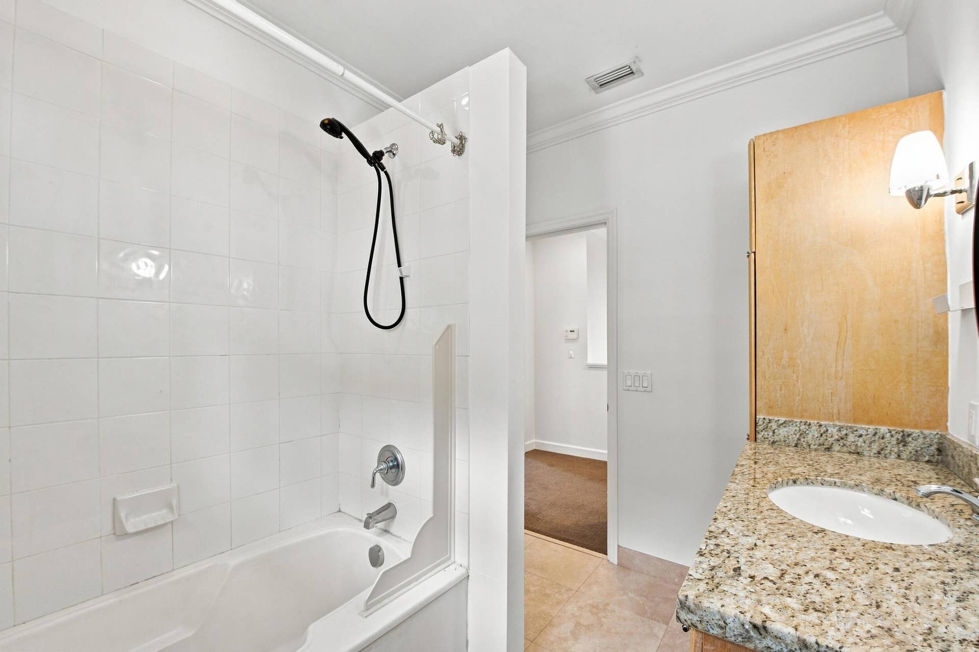 White tile bathtub and shower combination with a handheld showerhead
