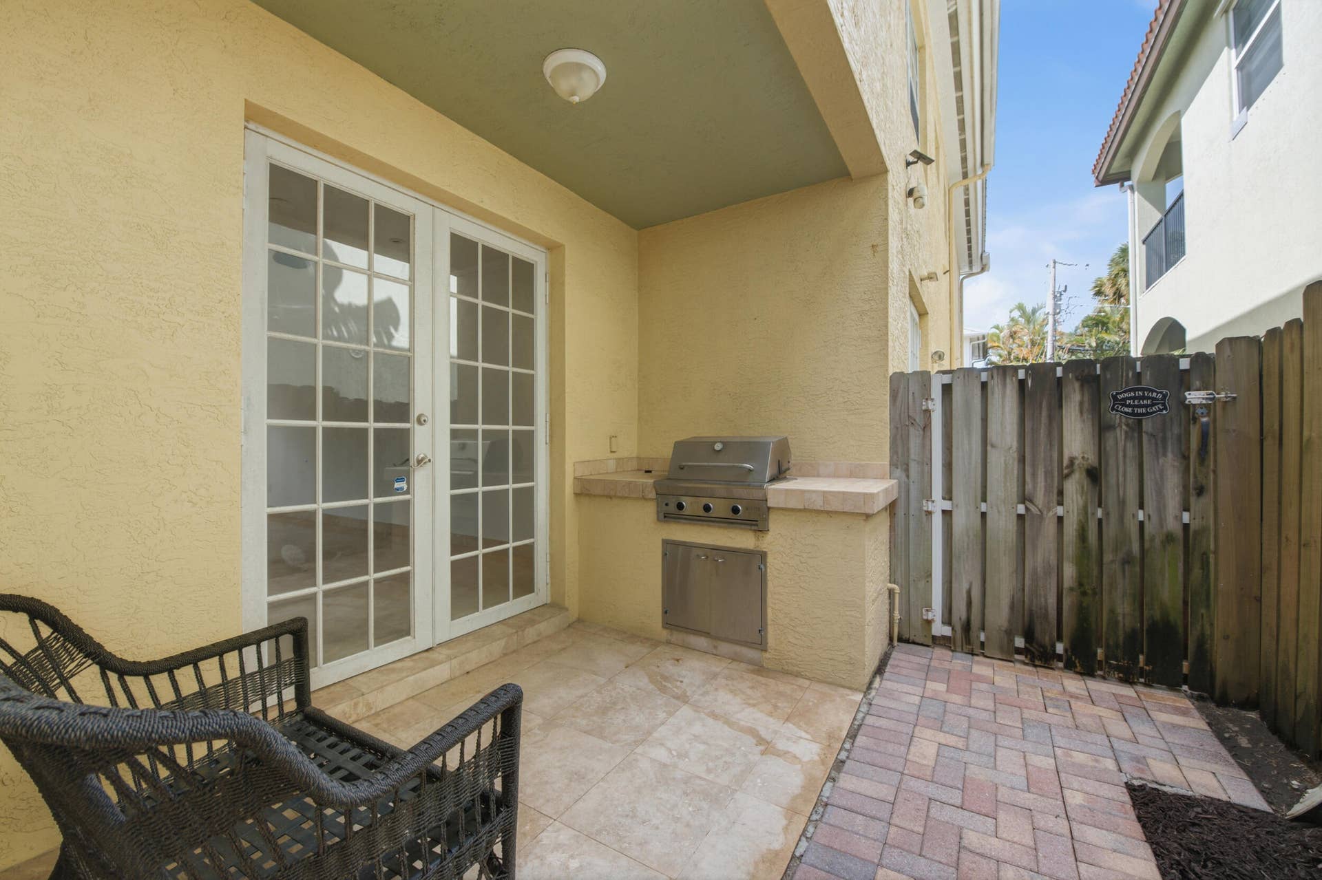 Covered patio area featuring French doors, an integrated outdoor grill, and stone tile flooring