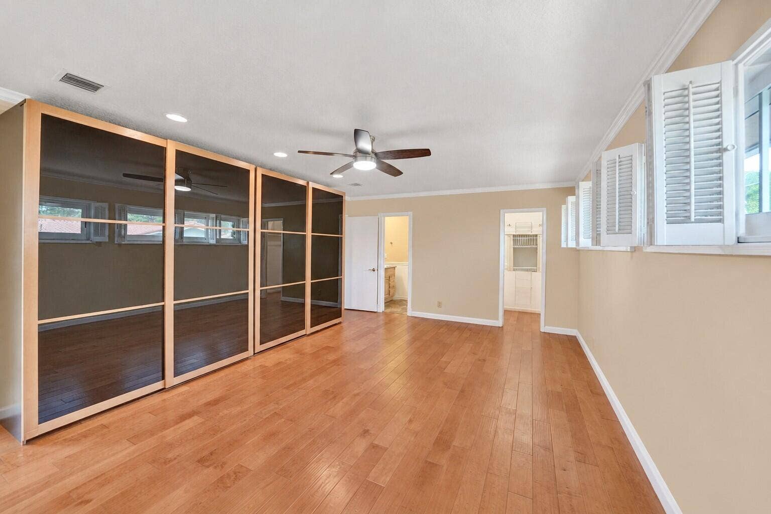 Hardwood flooring, recessed lighting, ceiling fan, crown molding, and built-in cabinetry with glass panel doors