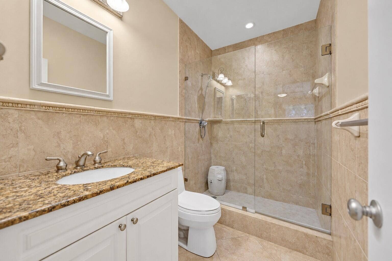 Vanity with an integrated sink, granite countertop, and white cabinetry