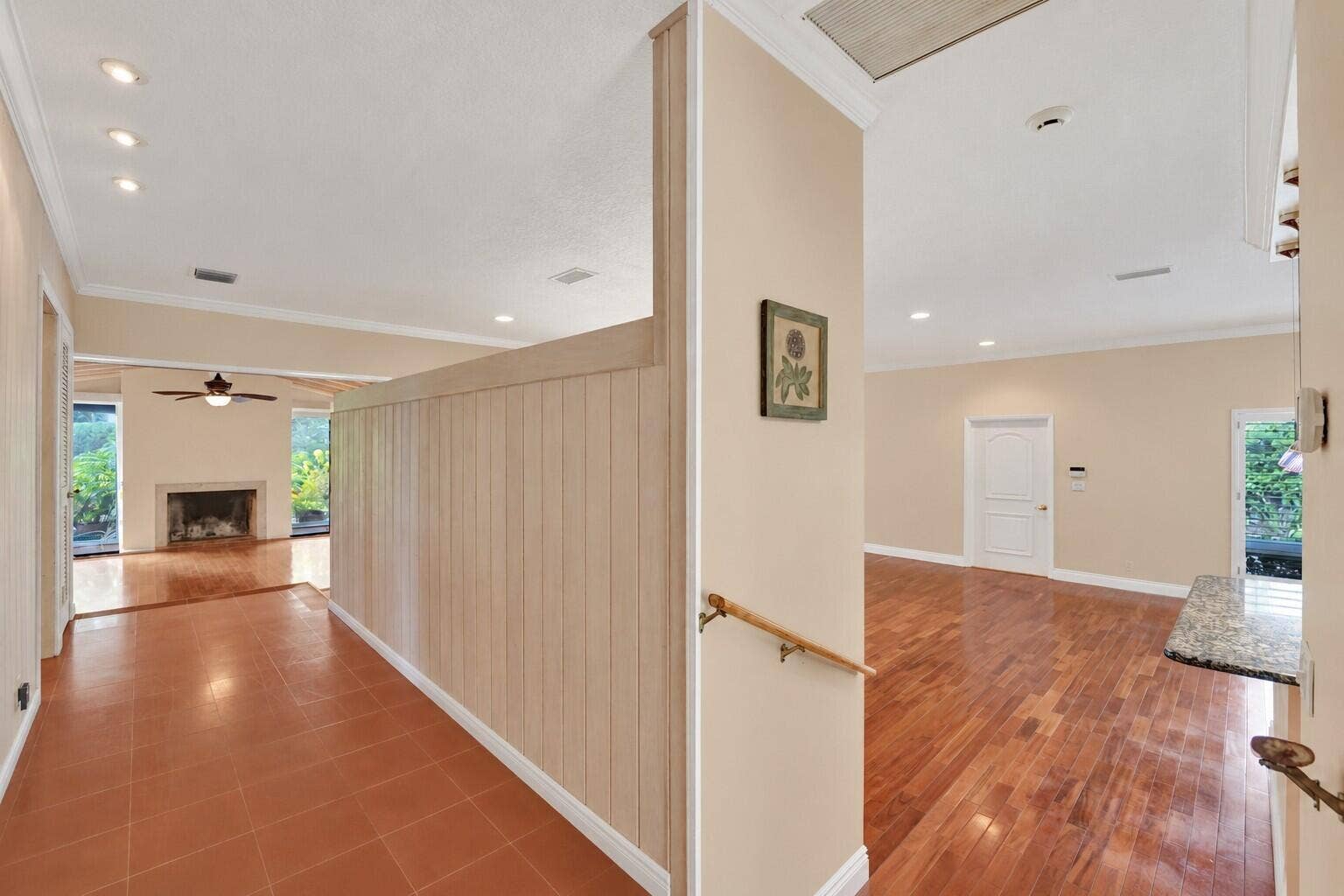 Recessed lighting, wood-finish flooring, terra cotta tile, built-in fireplace, and a light wood handrail. Wall color has been virtually altered.