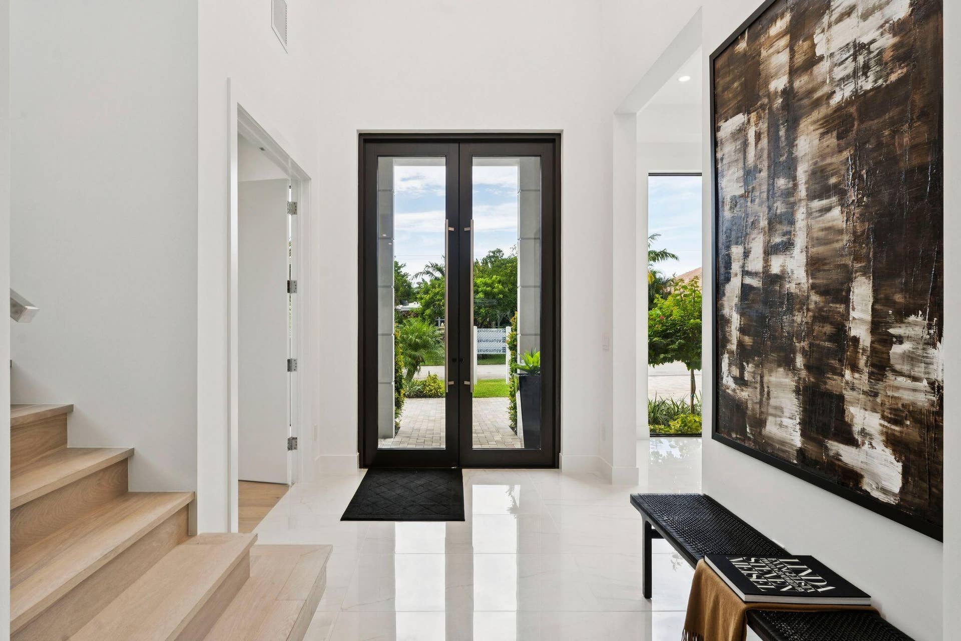 Entryway featuring double glass-paneled doors, wood-finish staircase, and polished tile flooring