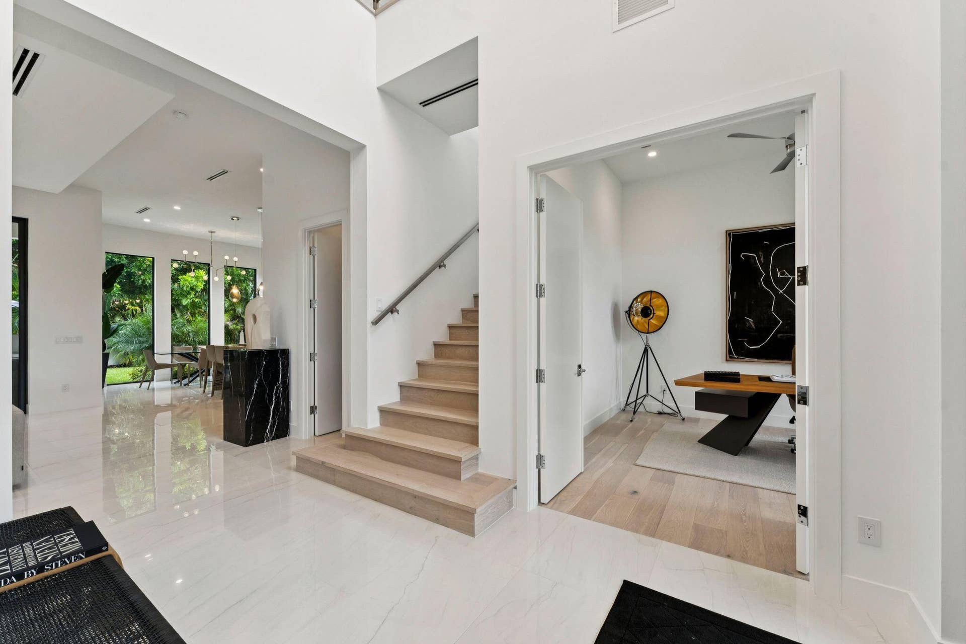 Polished tile flooring, a built-in staircase with a metal handrail, and high ceilings