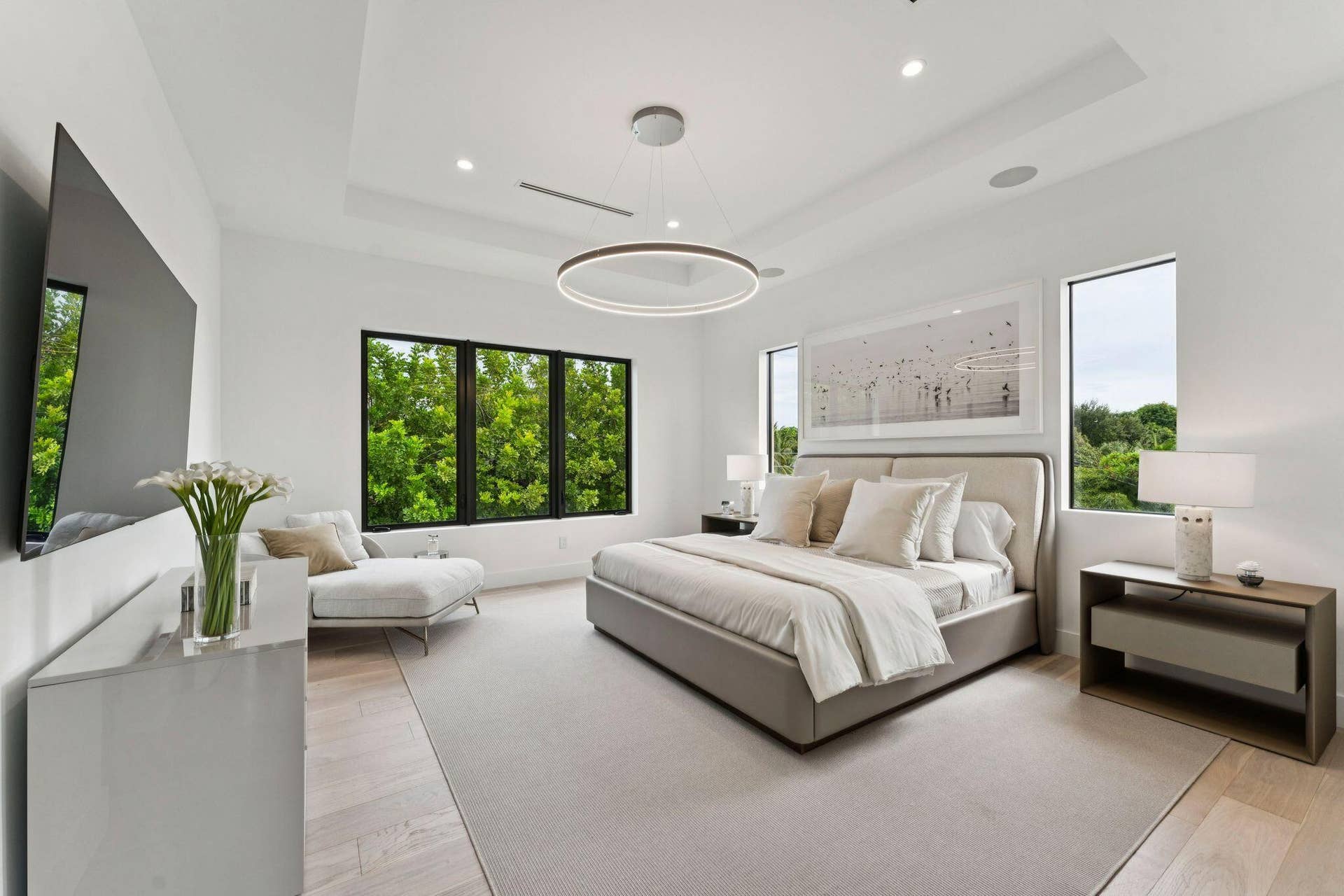 Recessed lighting, light wood-finish flooring, tray ceiling, and large windows with black frames