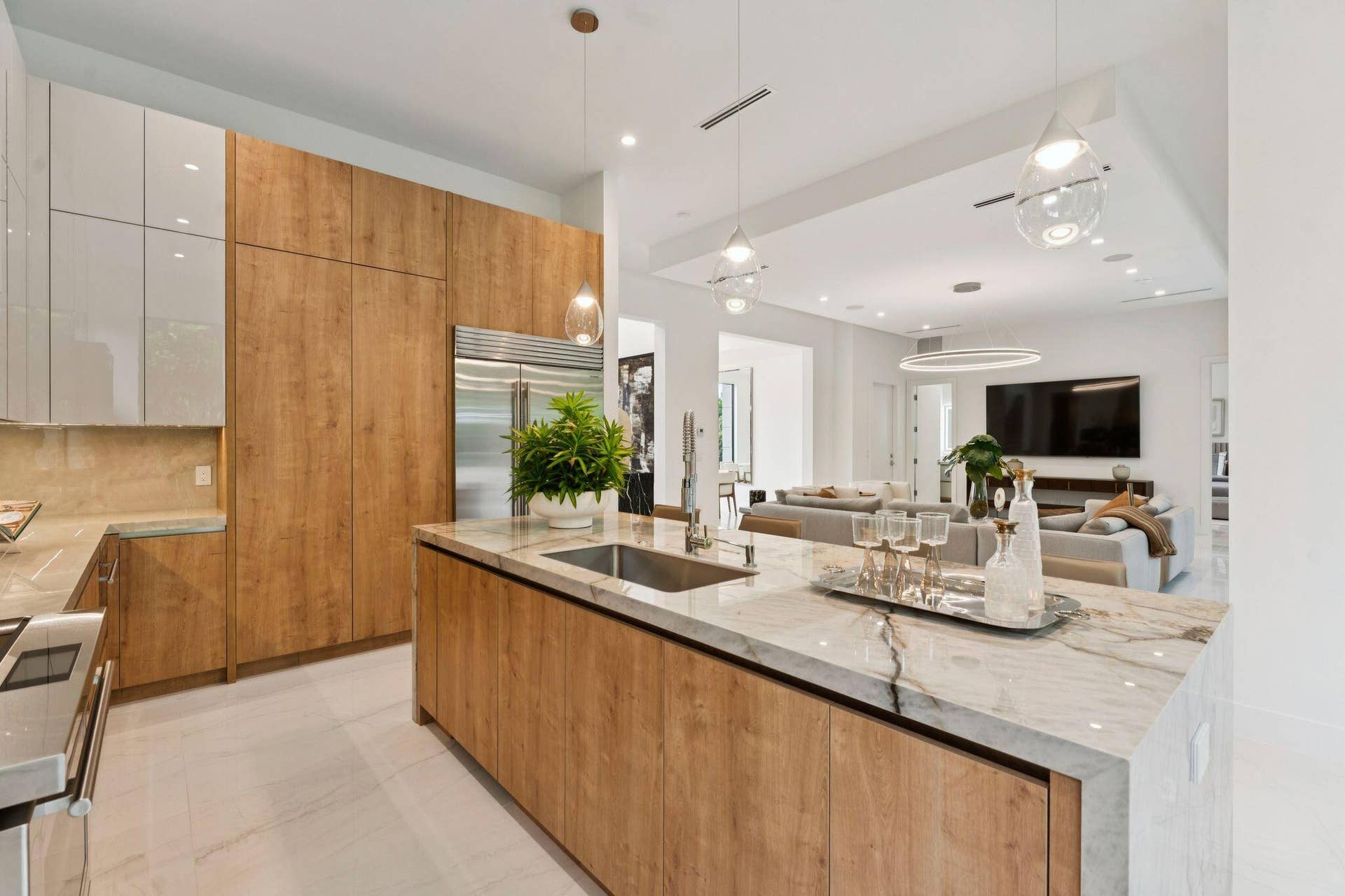 Kitchen featuring light wood-finish cabinetry, light stone countertops, integrated sink, and stainless steel refrigerator