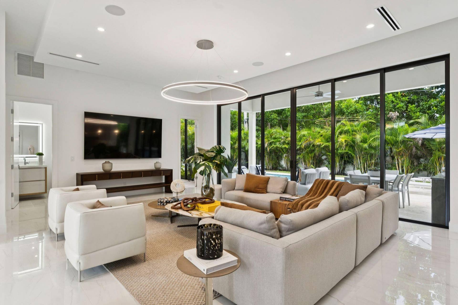 Spacious living area featuring polished tile flooring, recessed lighting, and a contemporary circular chandelier