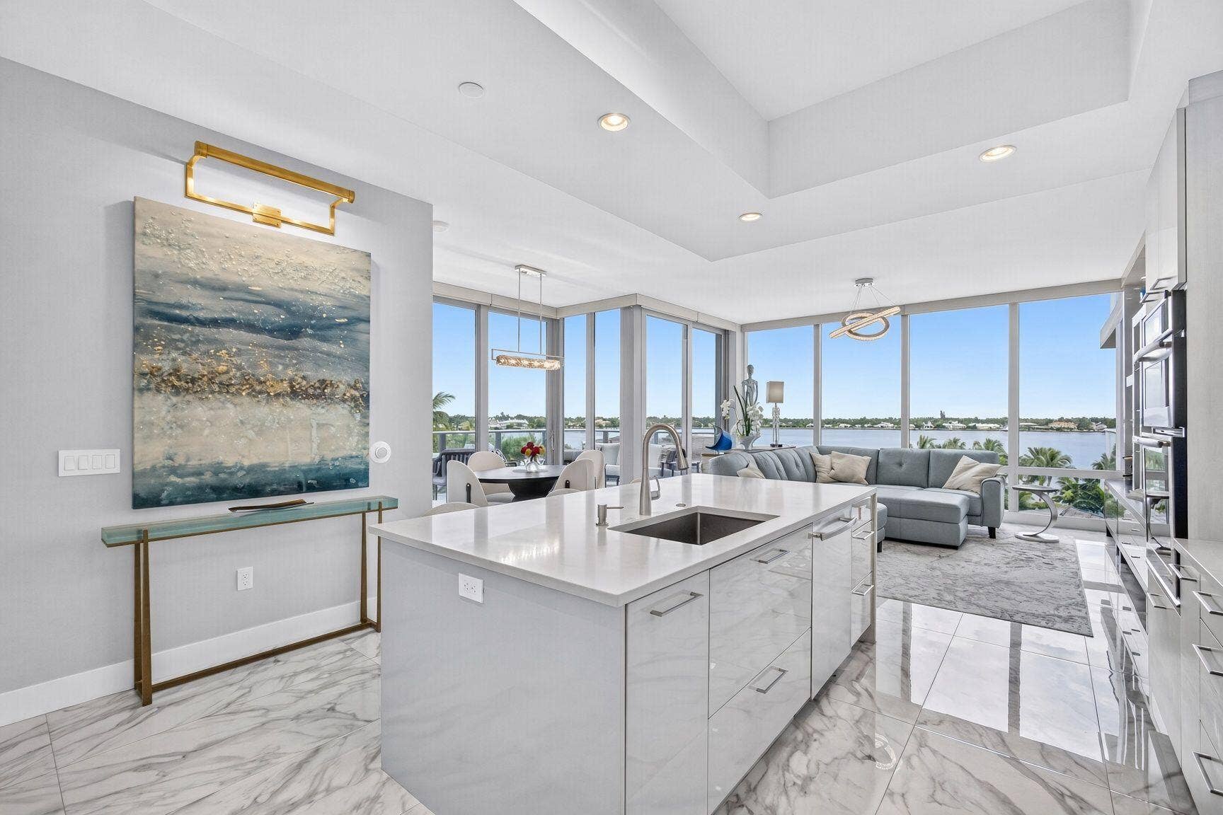 1 Water Club Way, #503, North Palm Beach, FL 33408 Open-concept living space with expansive floor-to-ceiling windows, a large kitchen island with an undermount sink, built-in ovens, and a coffered ceiling
