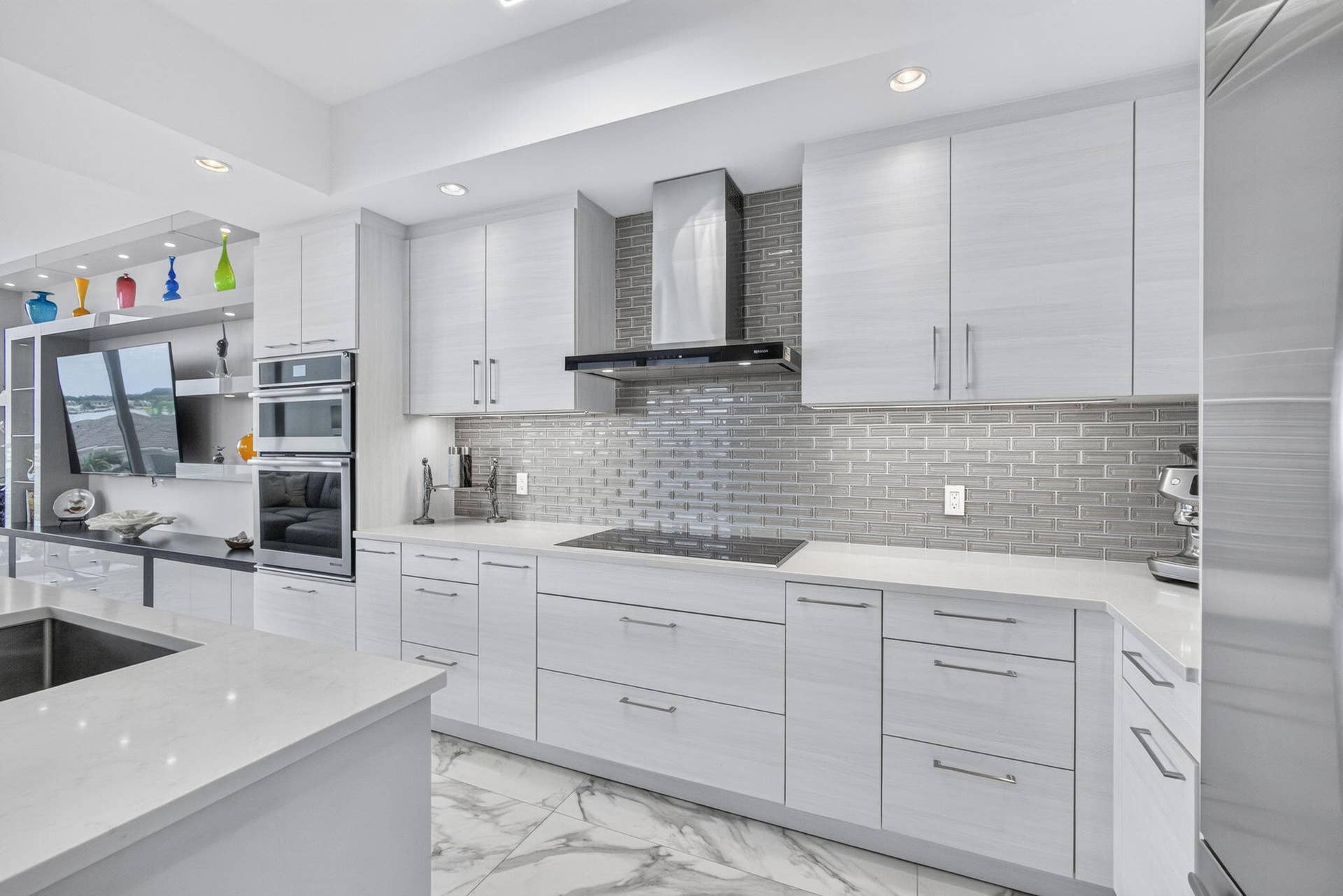 1 Water Club Way, #503, North Palm Beach, FL 33408 Sleek kitchen featuring light-toned cabinetry, a subway tile backsplash, and integrated High-end stainless steel appliances