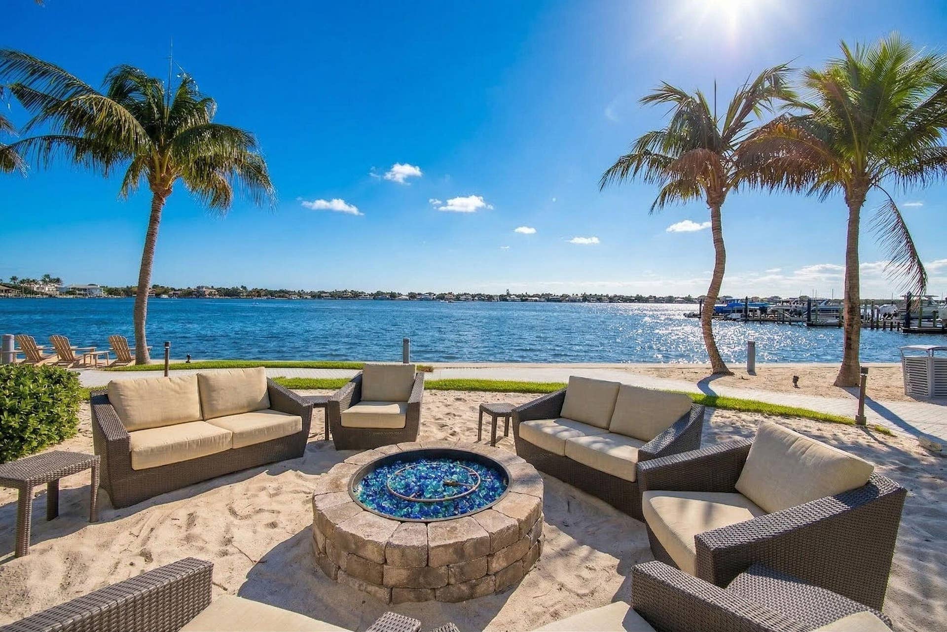1 Water Club Way, #503, North Palm Beach, FL 33408 Waterfront setting featuring a sandy lounging area, stone fire pit, and mature palm trees