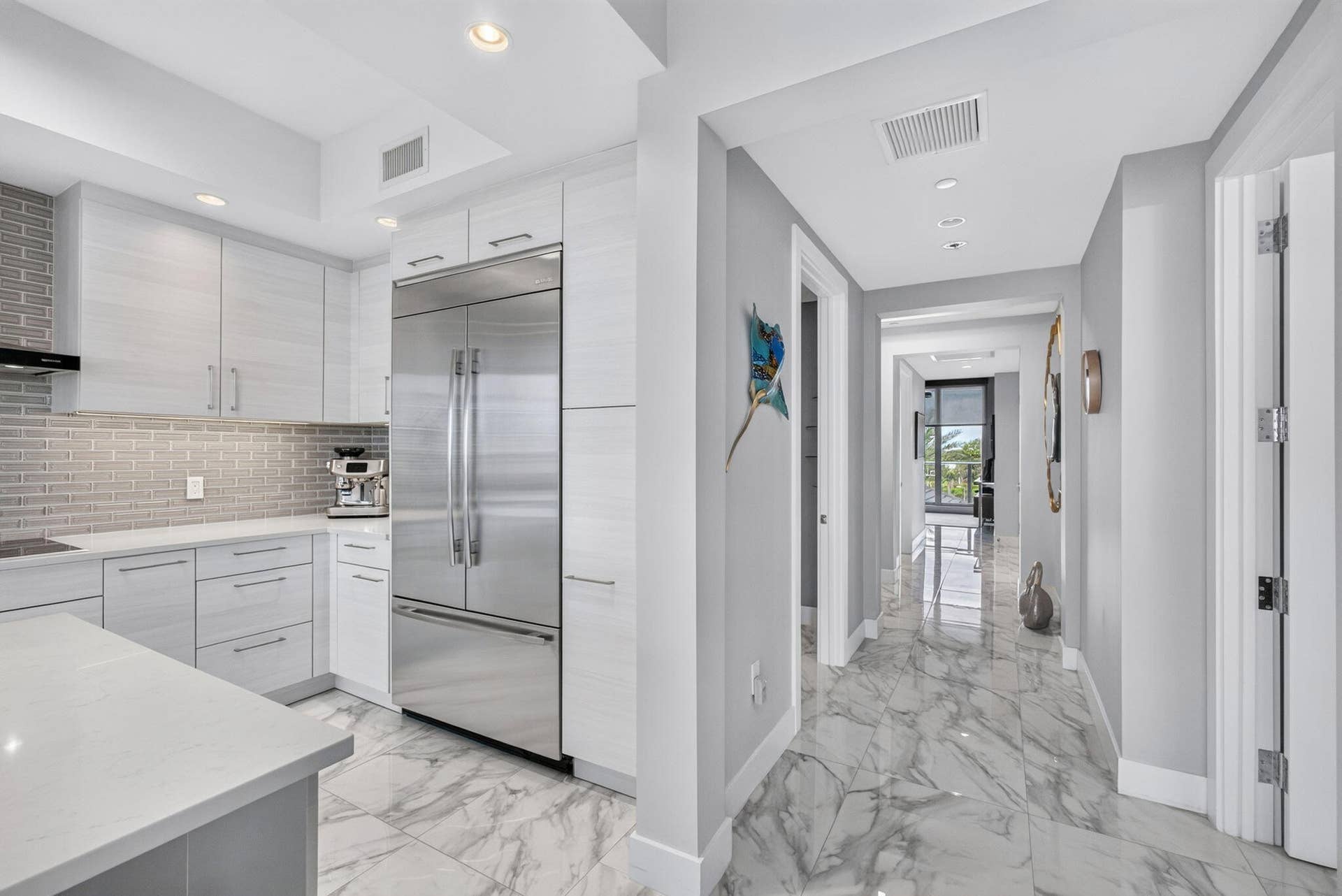 1 Water Club Way, #503, North Palm Beach, FL 33408 Modern kitchen featuring light-toned cabinetry, stainless steel appliances, and a tiled backsplash